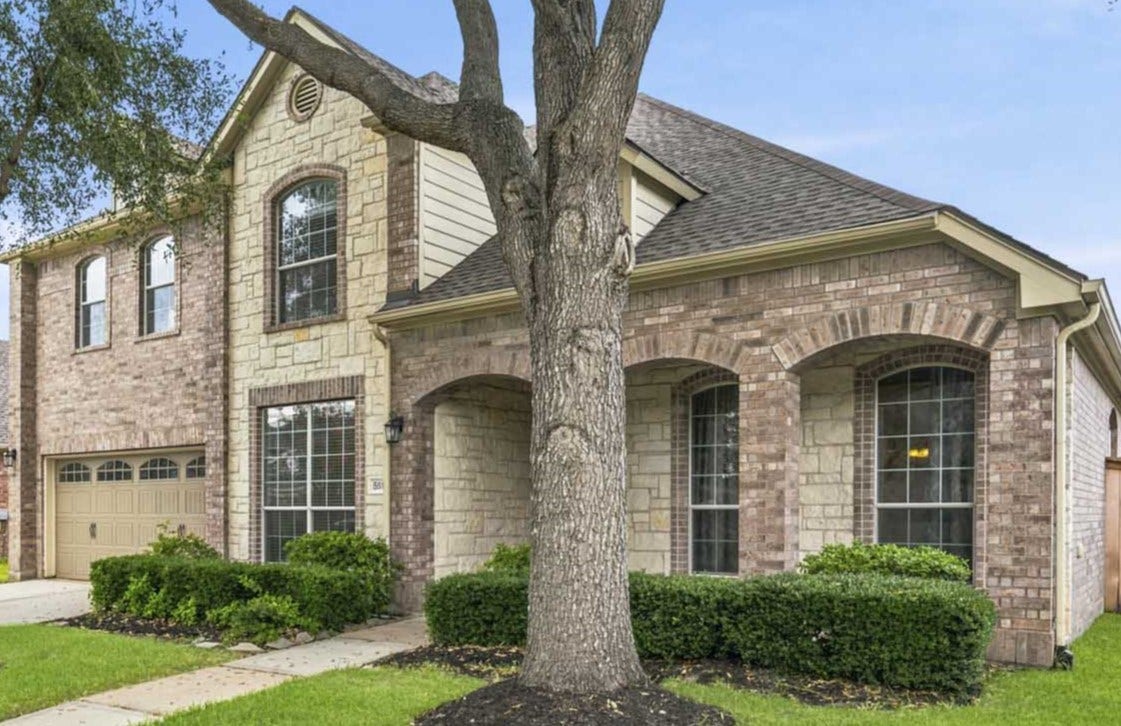 5515 Granite Meadow Drive, Katy, TX 77494 Front elevation featuring mature oak trees, lush landscaping, and the home's recently installed roof.