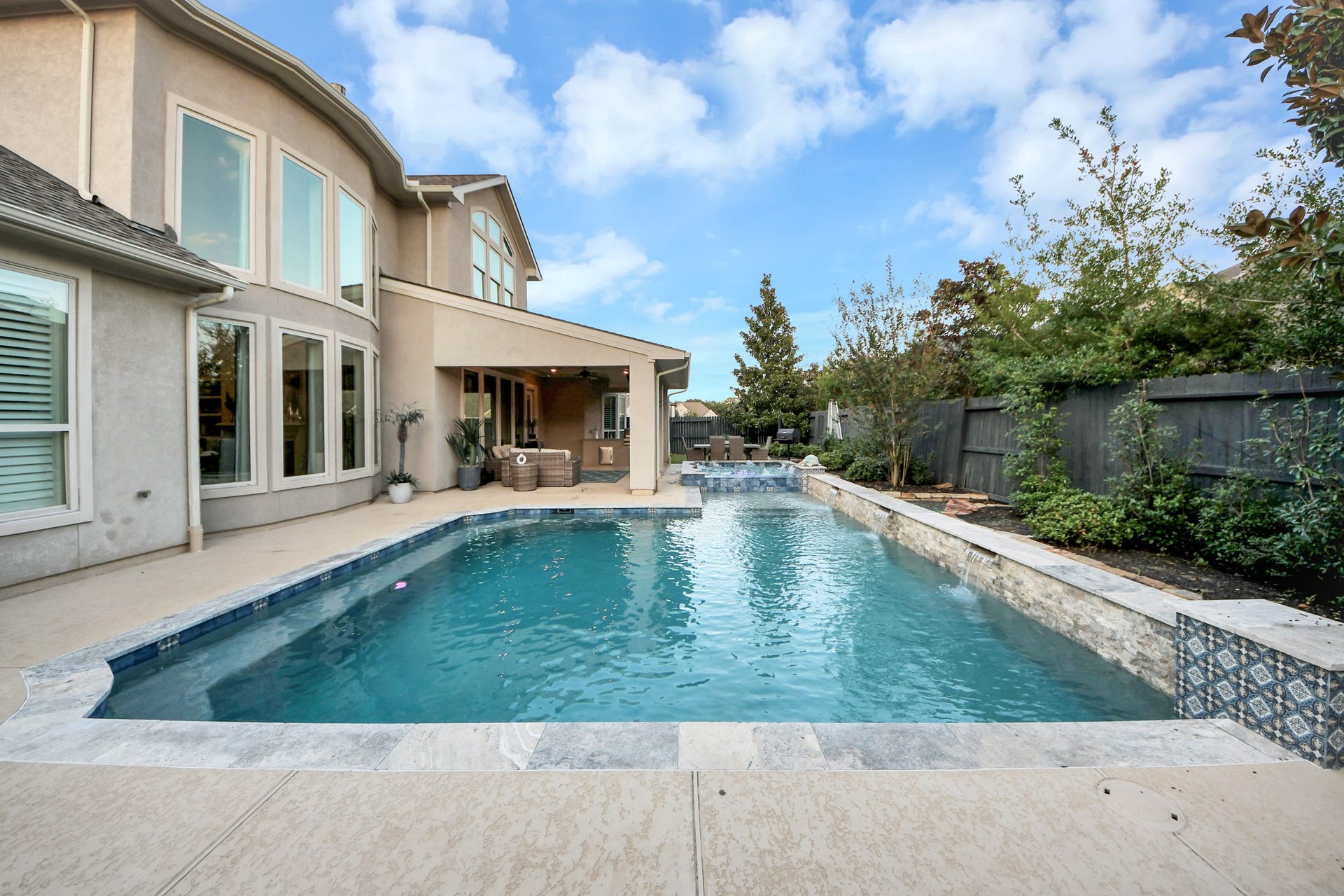 12821 N Palomino Lake Circle, Cypress, TX 77429 Stunning oversized pool built in 2022, featuring three cascading waterfalls, a tanning ledge for in-water lounging, and built-in bench seating along the pool's perimeter. Designed for relaxation and entertaining, with a spacious spa and exceptional backyard privacy.