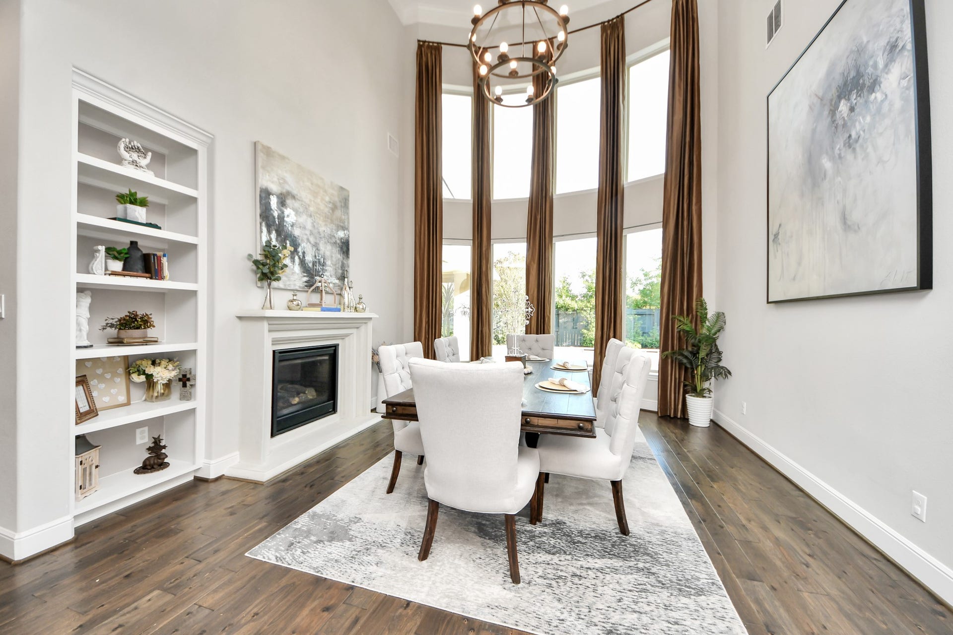 12821 N Palomino Lake Circle, Cypress, TX 77429 Elegant formal dining room featuring dramatic 20-foot ceilings, a double-sided fireplace, and expansive windows that fill the space with natural light.
