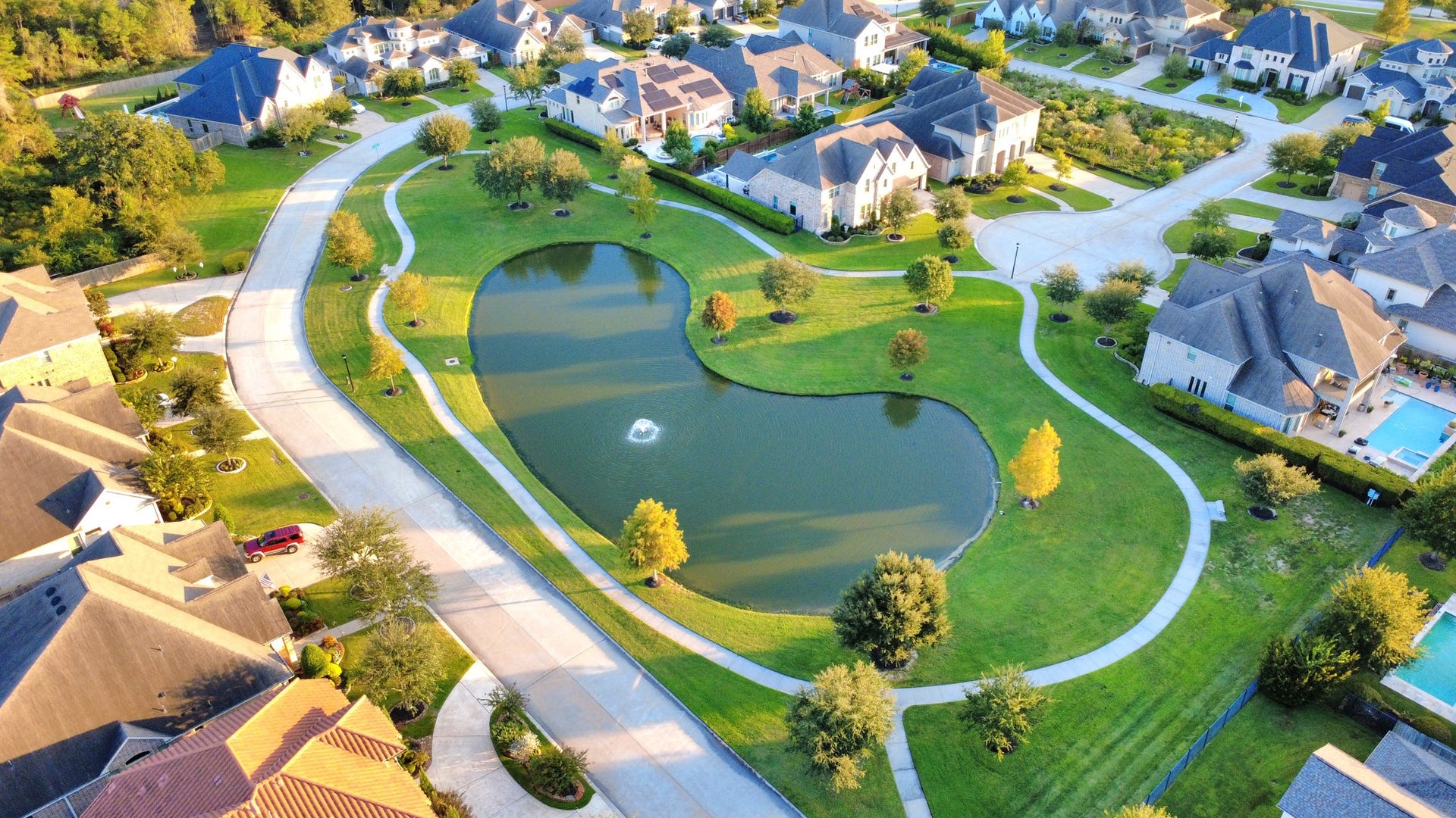 12821 N Palomino Lake Circle, Cypress, TX 77429 Beautiful aerial view of the gated Bridlecreek community, showcasing its scenic lake, lush green spaces, and walking trails surrounded by beautifully maintained homes and landscaping.