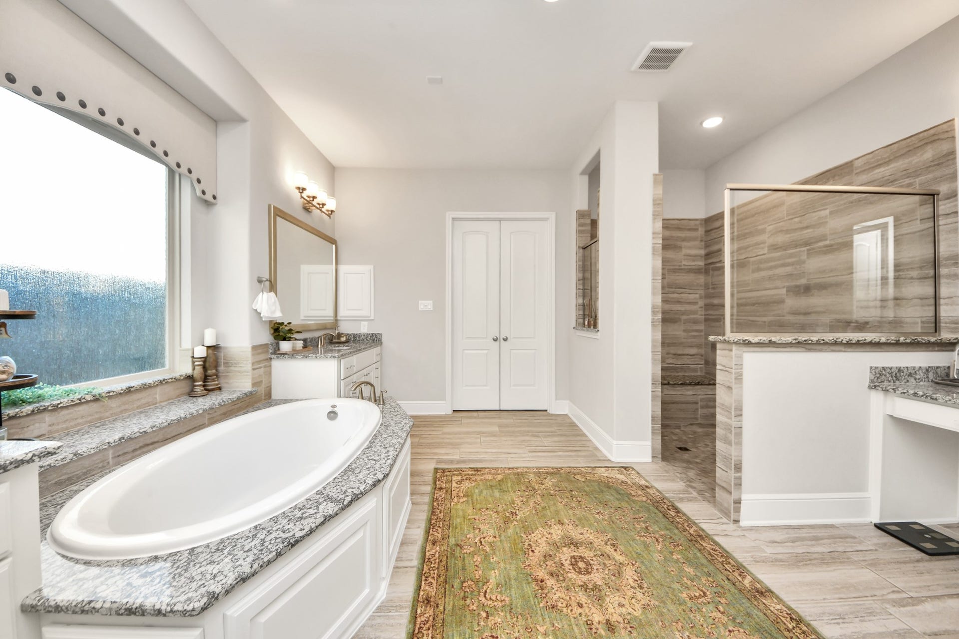 12821 N Palomino Lake Circle, Cypress, TX 77429 Luxurious primary bathroom featuring a spacious walk-in shower with built-in bench and a dedicated makeup vanity with an illuminated mirror.