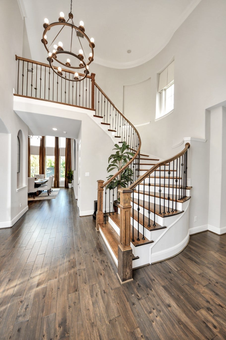 12821 N Palomino Lake Circle, Cypress, TX 77429 Grand entry featuring a stunning spiral staircase, statement chandelier, rich hardwood floors, and dramatic 20-foot ceilings, all beautifully illuminated by abundant natural light.
