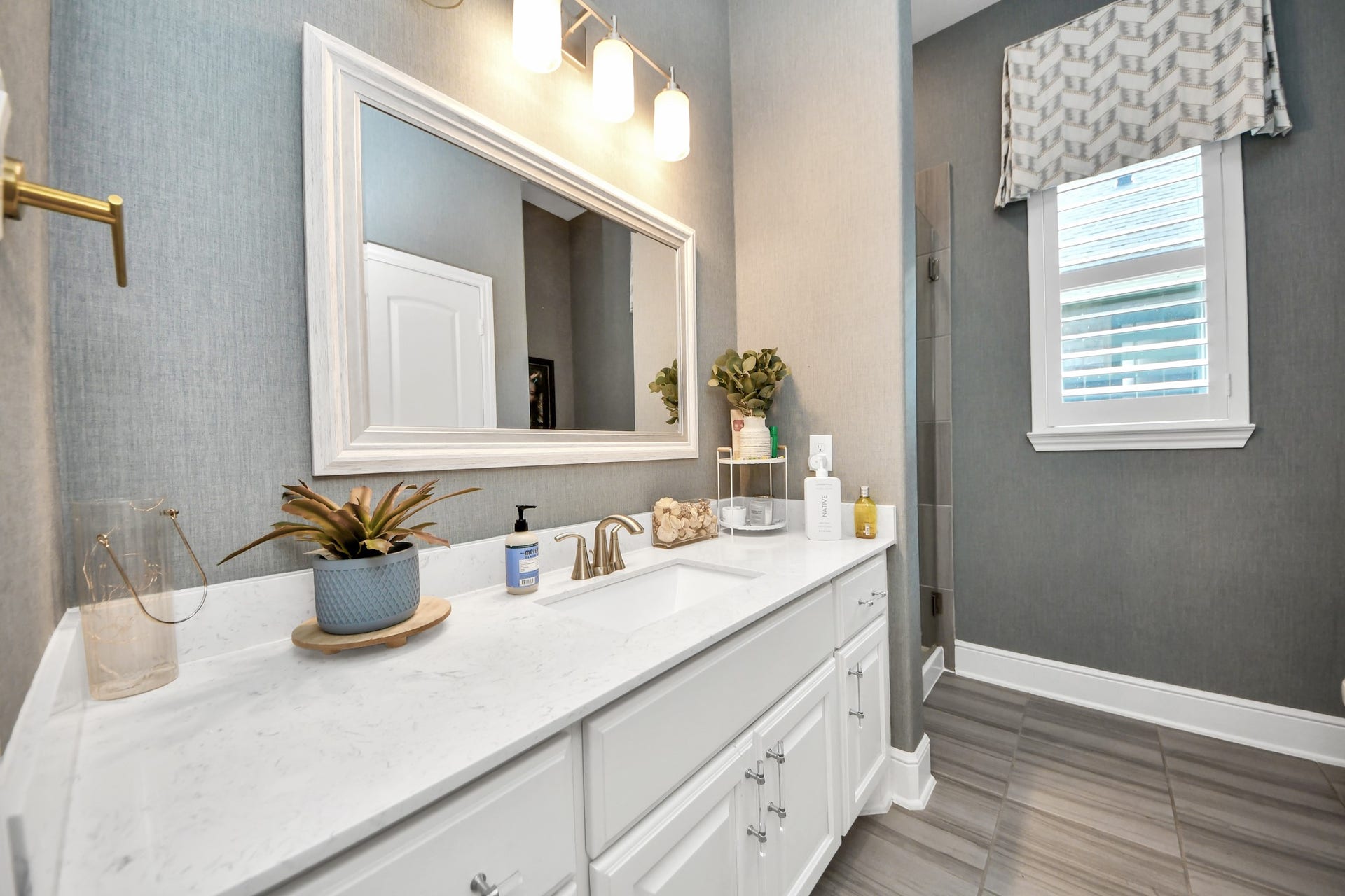 12821 N Palomino Lake Circle, Cypress, TX 77429 Third full bathroom on the first floor, featuring quartz countertops, decorative wallpaper, plantation shutters, and a walk-in shower with frameless glass enclosure.