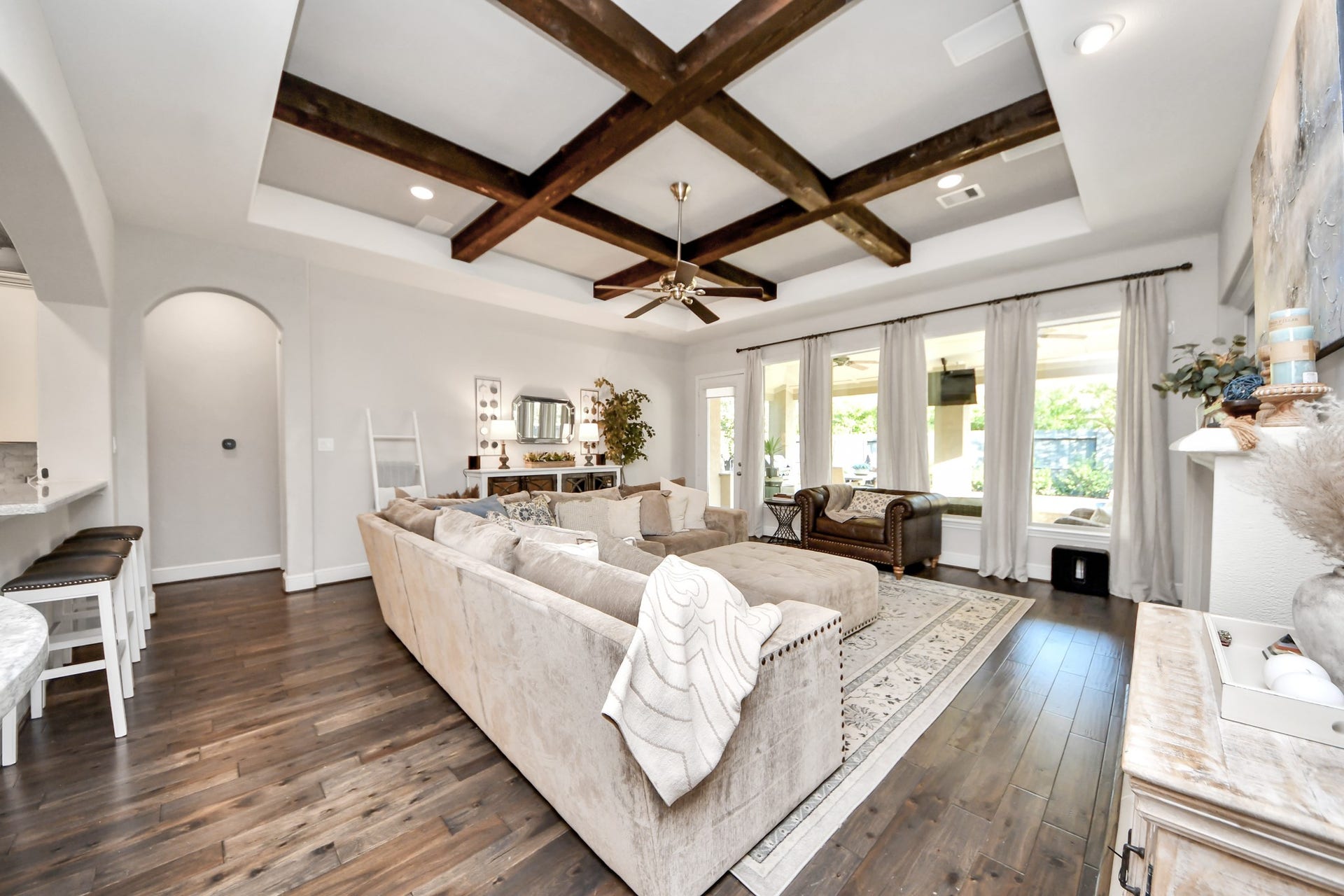 12821 N Palomino Lake Circle, Cypress, TX 77429 Spacious family room featuring a coffered-style ceiling with exposed wood beams, built-in surround sound speakers, and remote-controlled automatic window coverings.