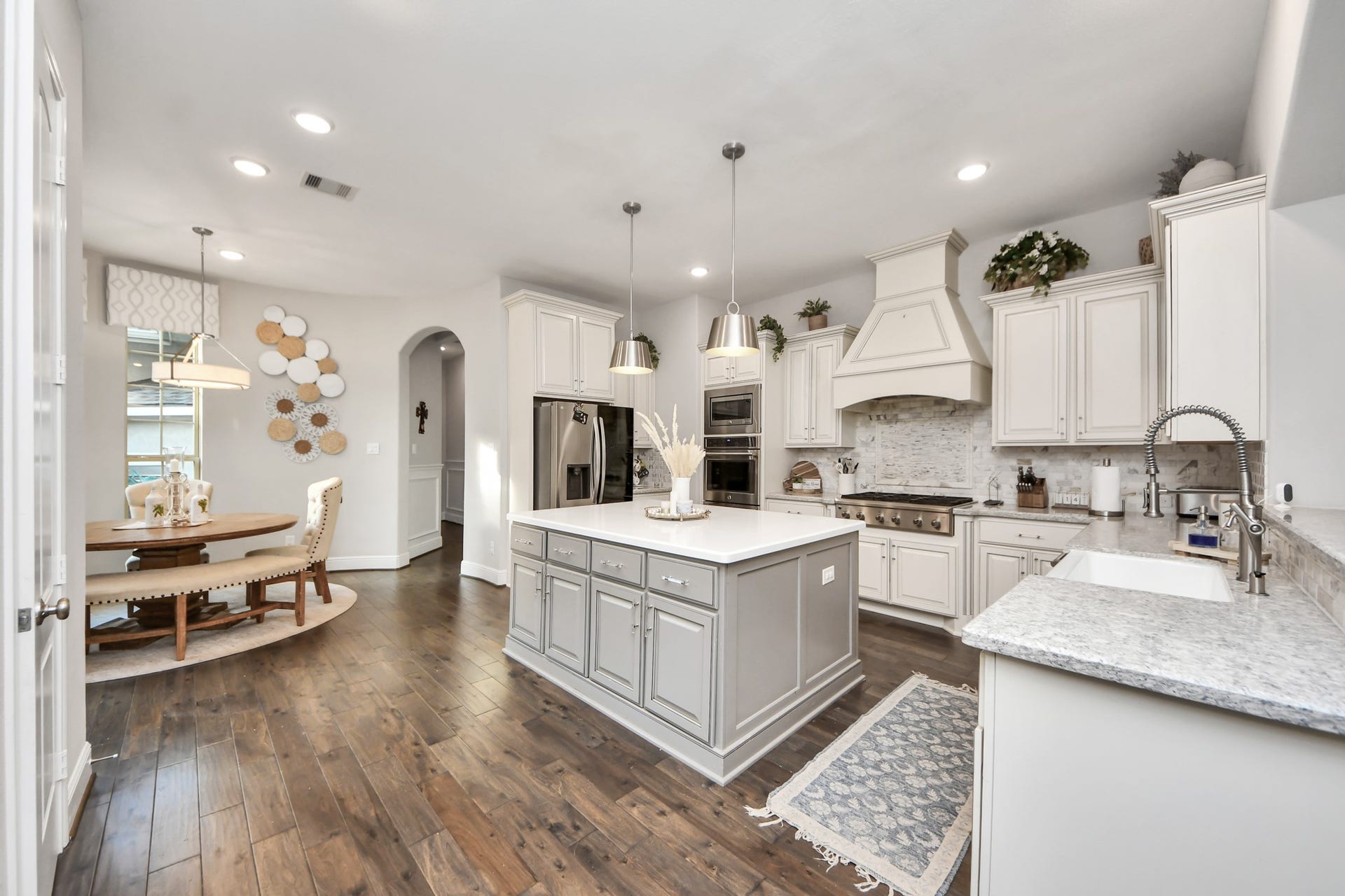 12821 N Palomino Lake Circle, Cypress, TX 77429 Gourmet kitchen featuring quartz countertops, a spacious center island, double ovens, six-burner cooktop, custom built-in vent hood, stainless steel appliances, and lower cabinetry equipped with custom pullout drawers and organizational storage.