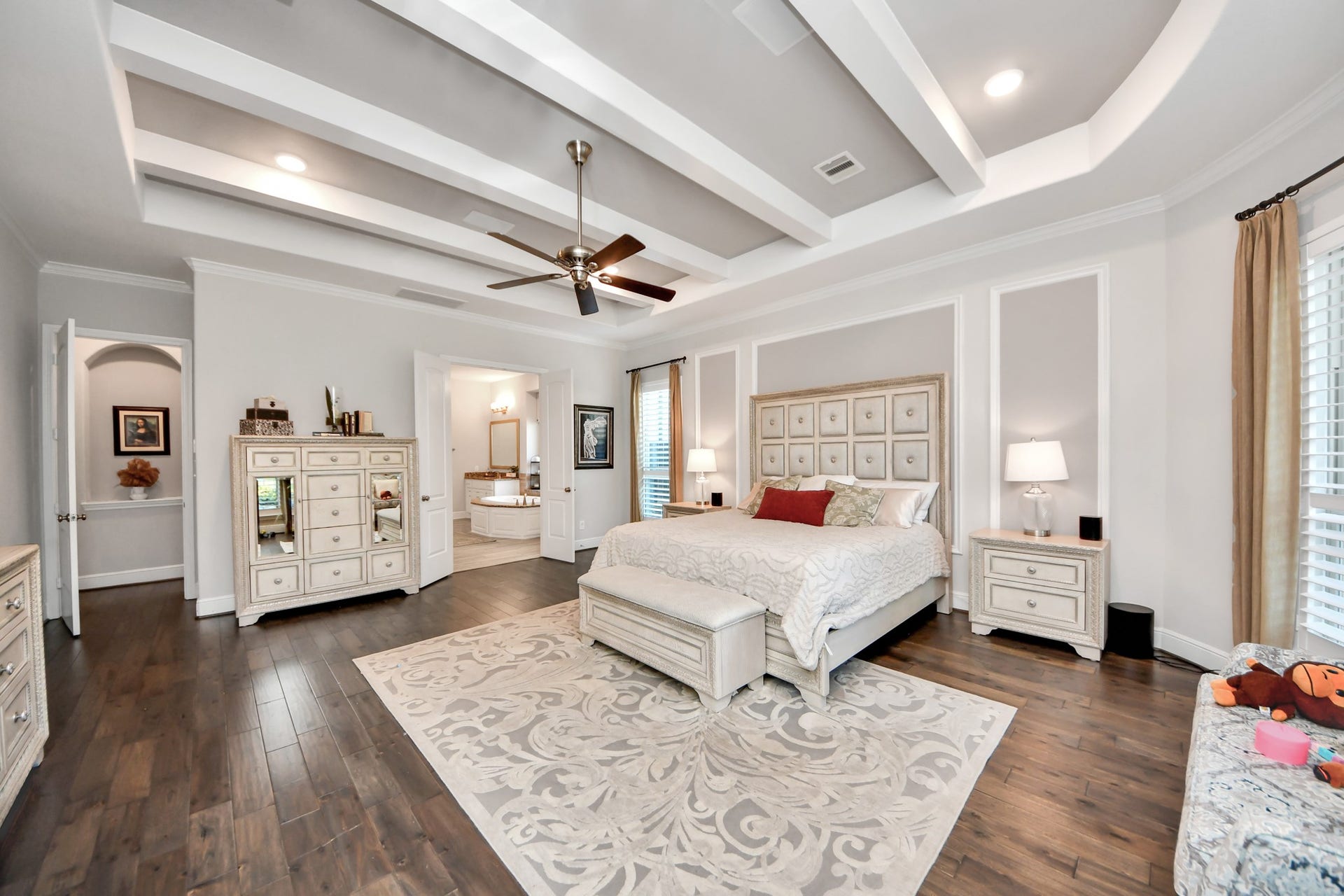 12821 N Palomino Lake Circle, Cypress, TX 77429 Expansive primary suite featuring rich wood flooring, decorative ceiling beams, built-in surround sound speakers, and a spacious layout.