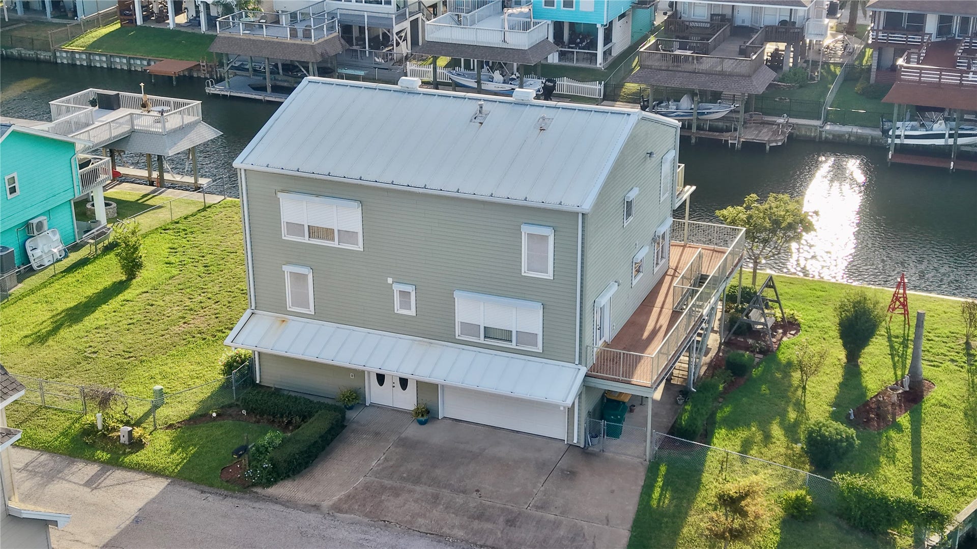 7 S Skimmer Street, La Marque, TX 77568 Aerial view of 7 S Skimmer Street: a 1996 custom steel-frame home on two lots, with a metal roof, a spacious yard, and a new vinyl bulkhead wrapping the waterfront.