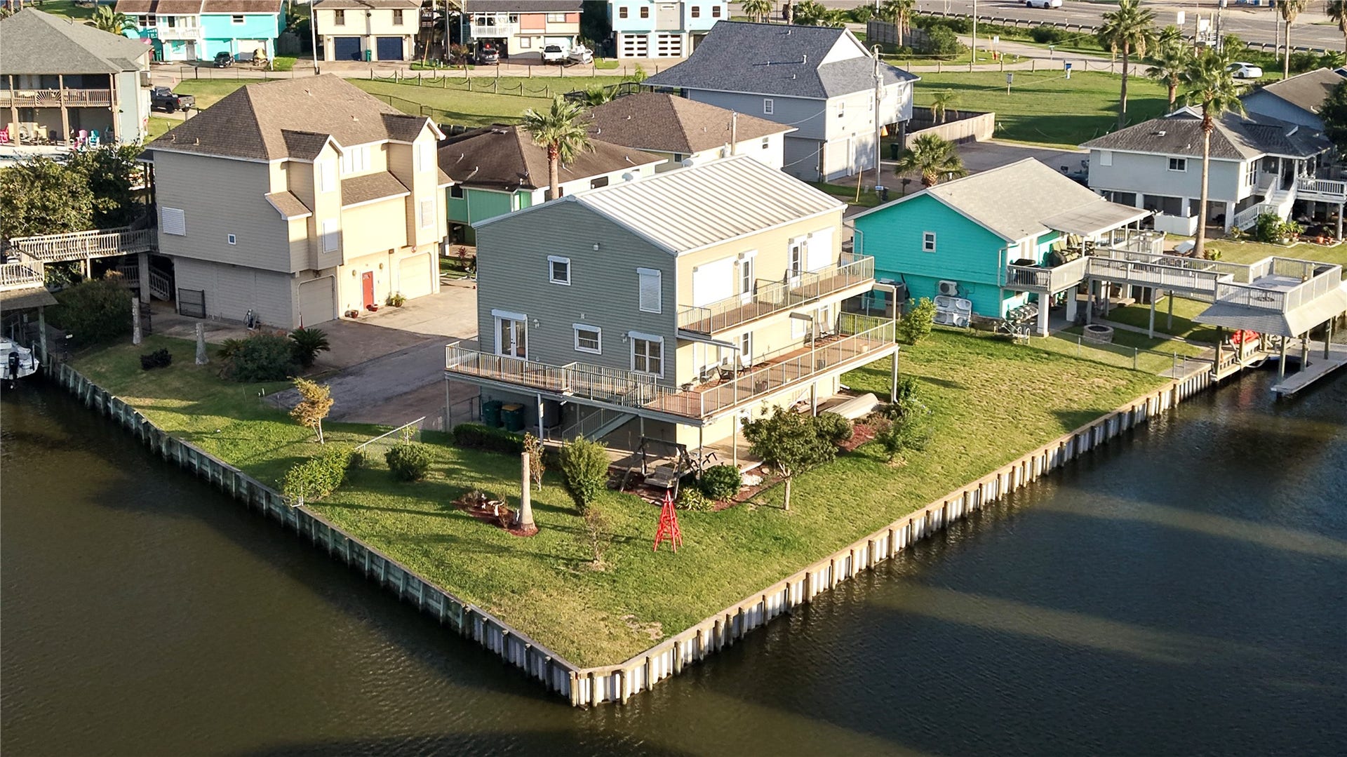 7 S Skimmer Street, La Marque, TX 77568 A closer look from the water side: two open-air balconies on the upper level, plus a wraparound deck below that's partly covered for shade. A wide lawn with established landscaping runs right to the new vinyl bulkhead. With two lots, there's room to spread out, entertain, and enjoy the waterfront from almost every angle.