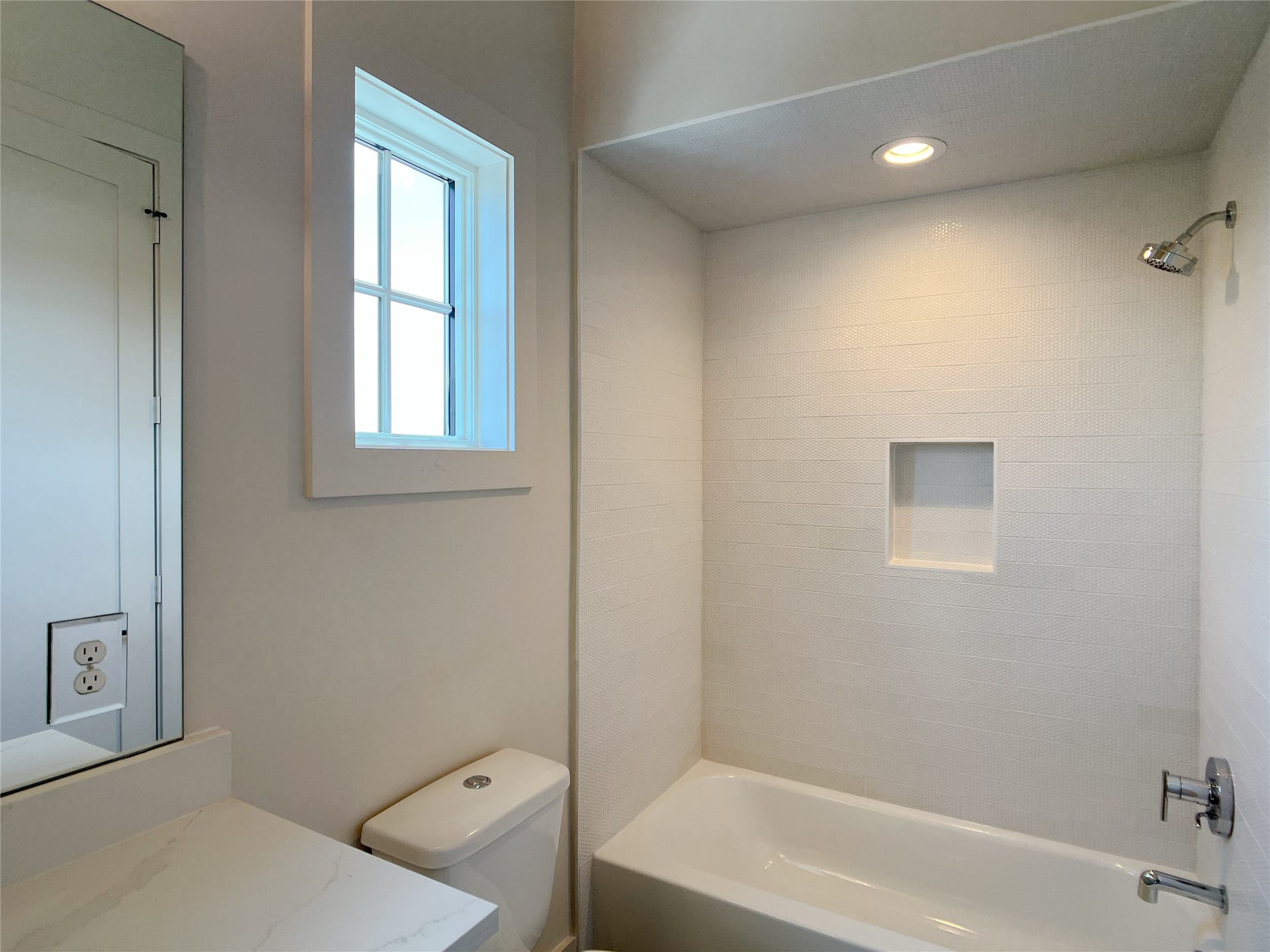 textured tiles surround shower from tub to ceiling & product niche