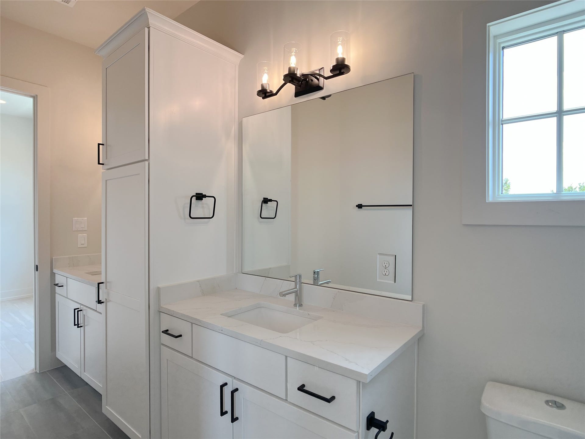 full bath shared between 2 secondary bedrooms w/dual vanities, linen cabinets, dual-flush toilet