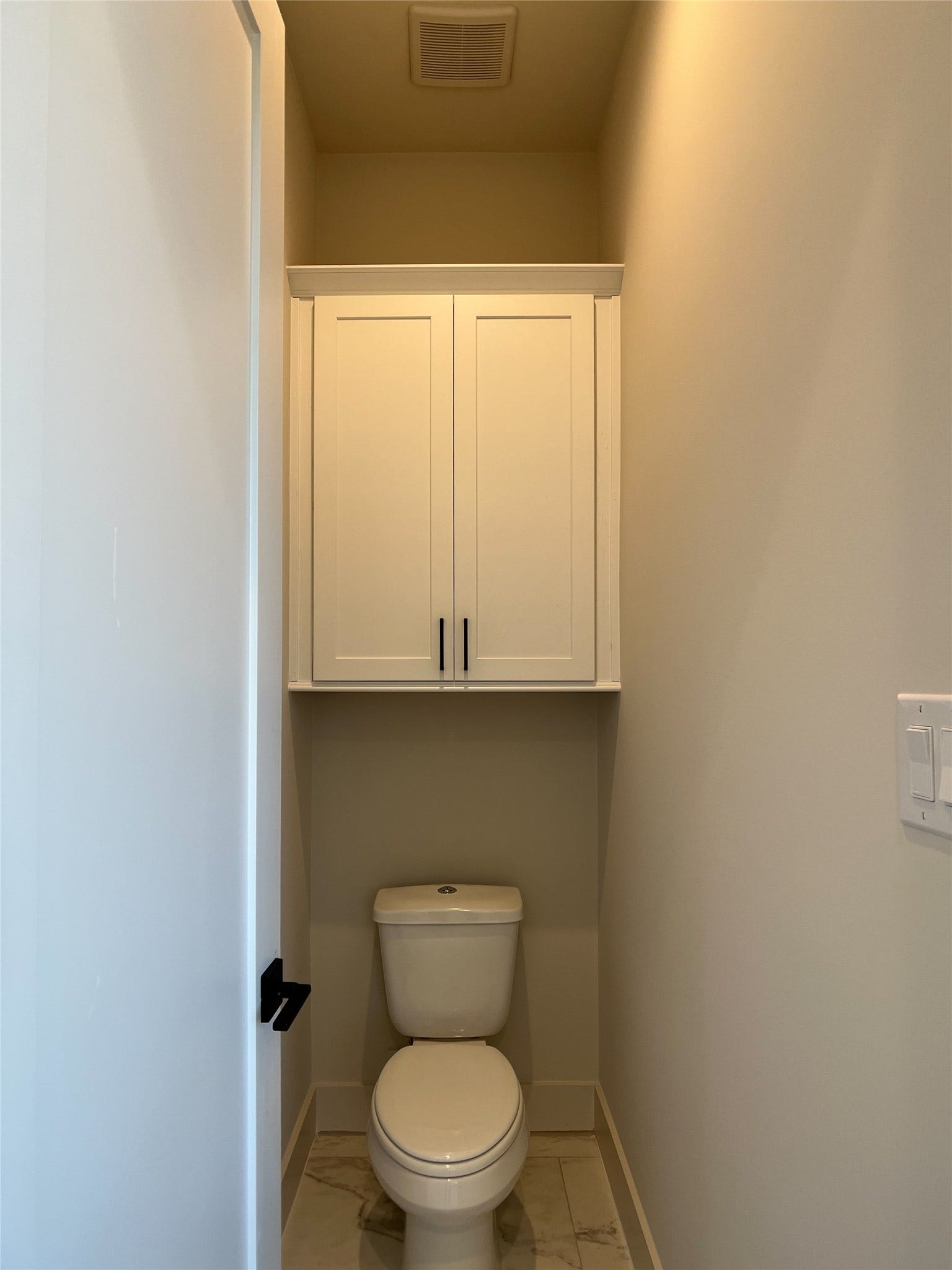 water closet w/cabinets for more storage above dual-flush toilet