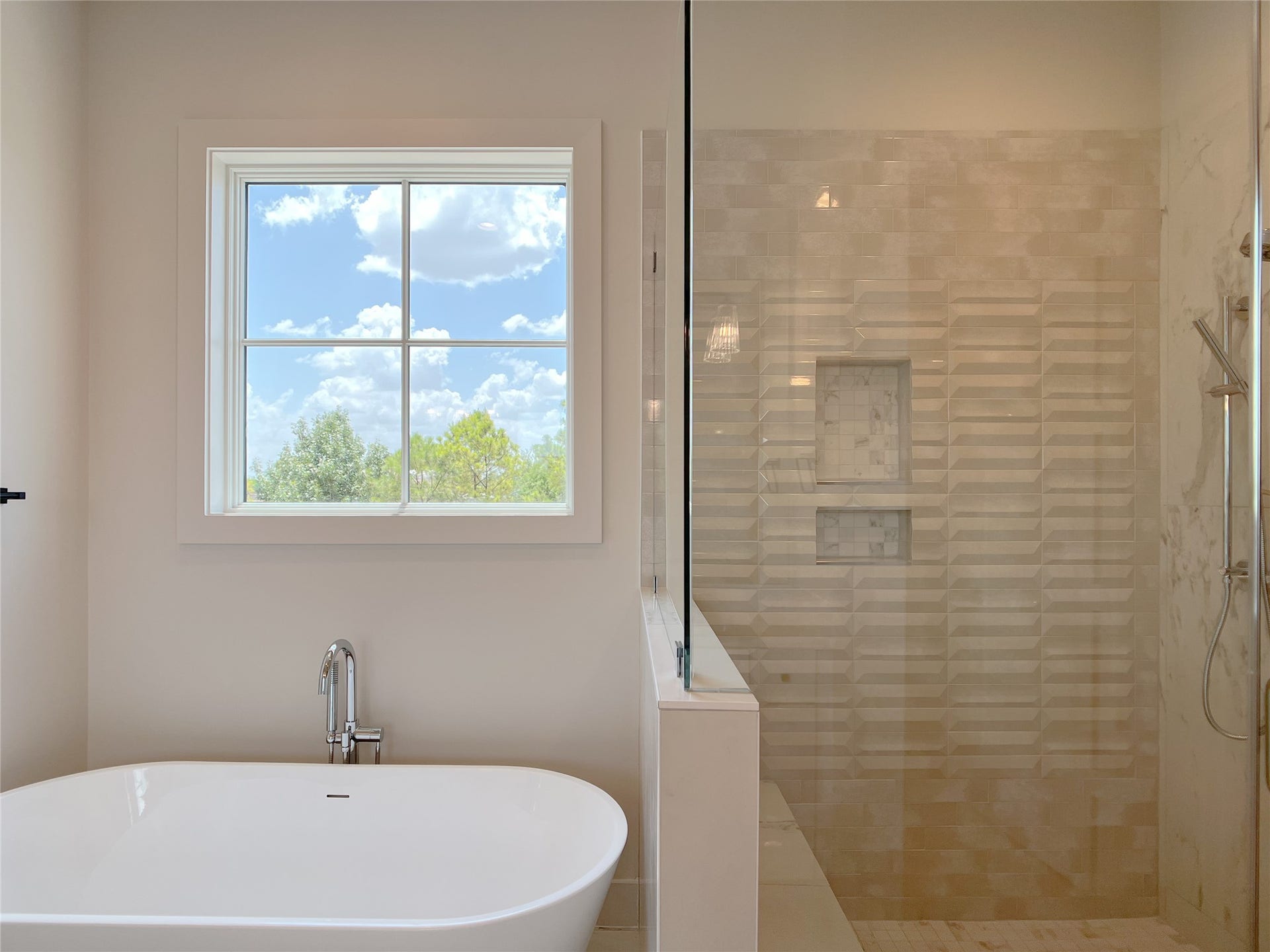 freestanding tub next to frameless glass shower w/designer tile on walls & floors