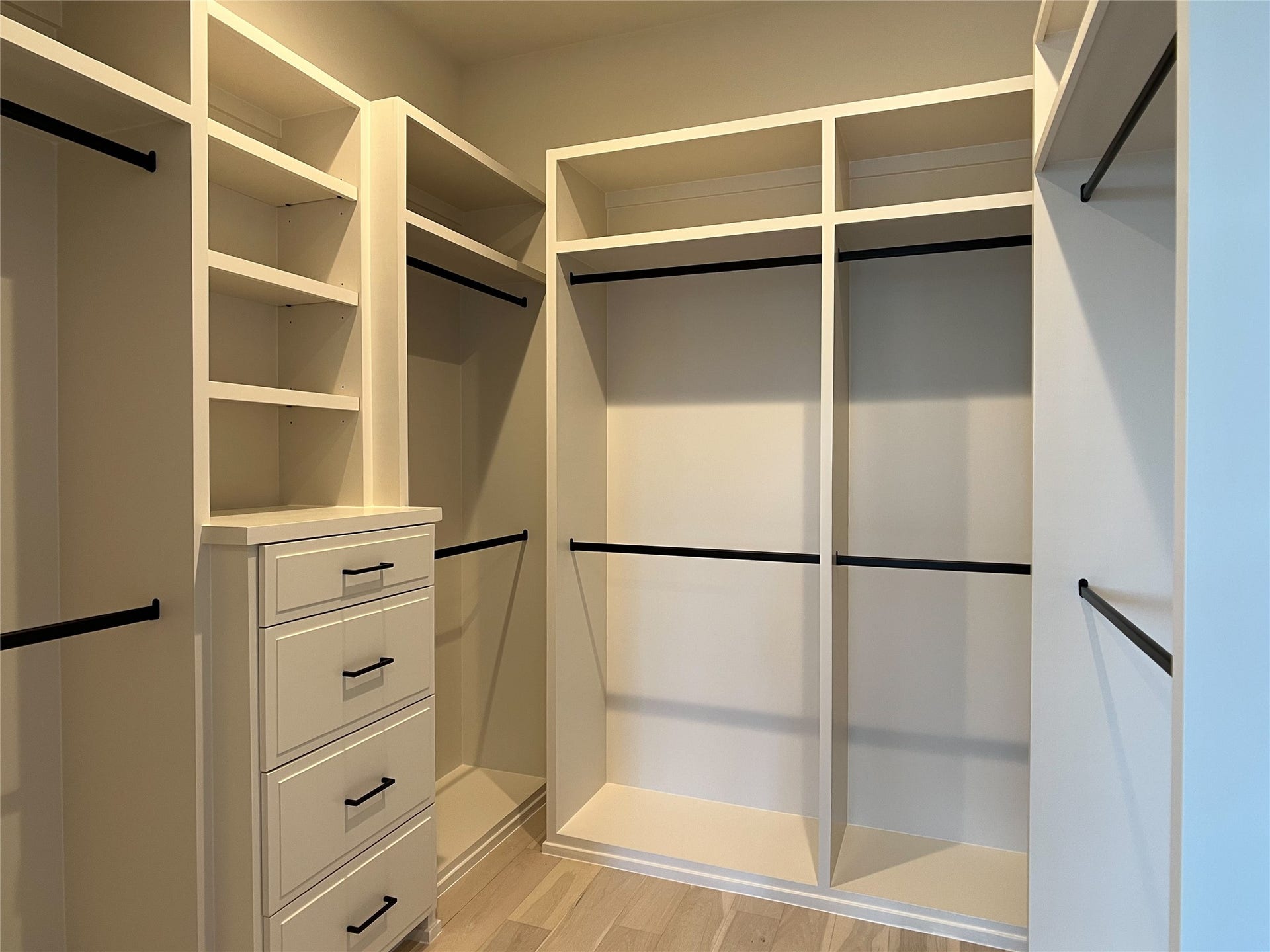 1 of 2 owner's walk-in closets w/custom, site-built cabinetry & matte black metal hanging rods