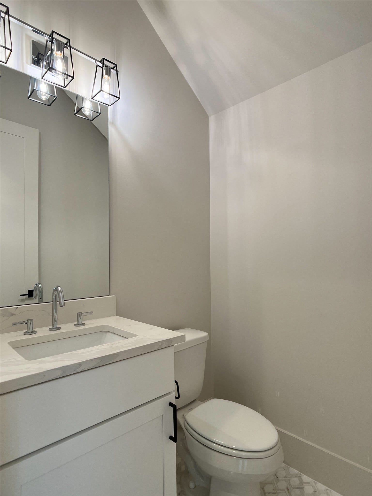 1st-floor powder room w/quartz countertop, elegant tile flooring, beautiful lighting