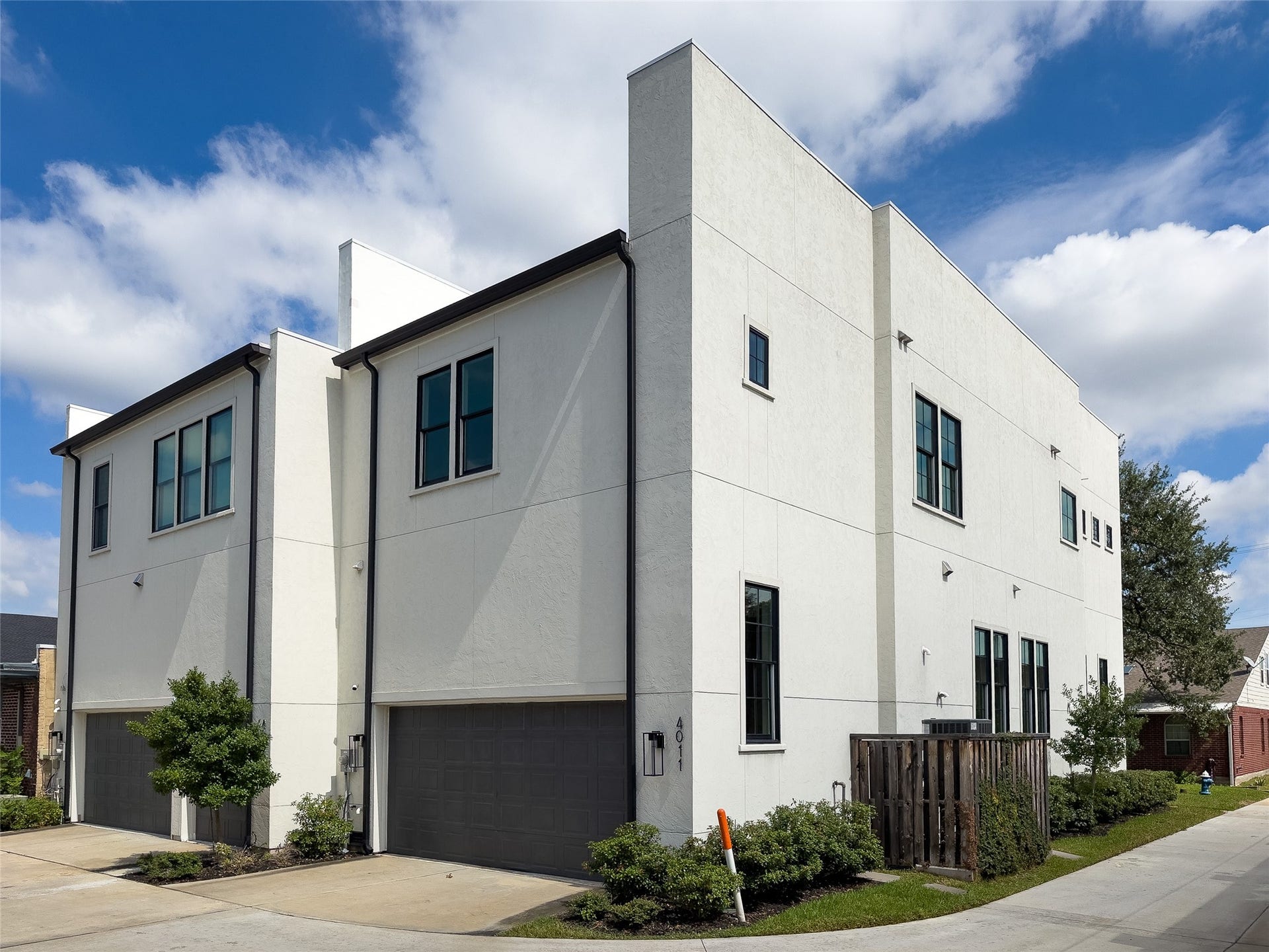 2-car garage w/attractive gray overhead door & driveway facing double-wide alley; end unit means adjoining neighbor on only one side; fenced-in HVAC unit