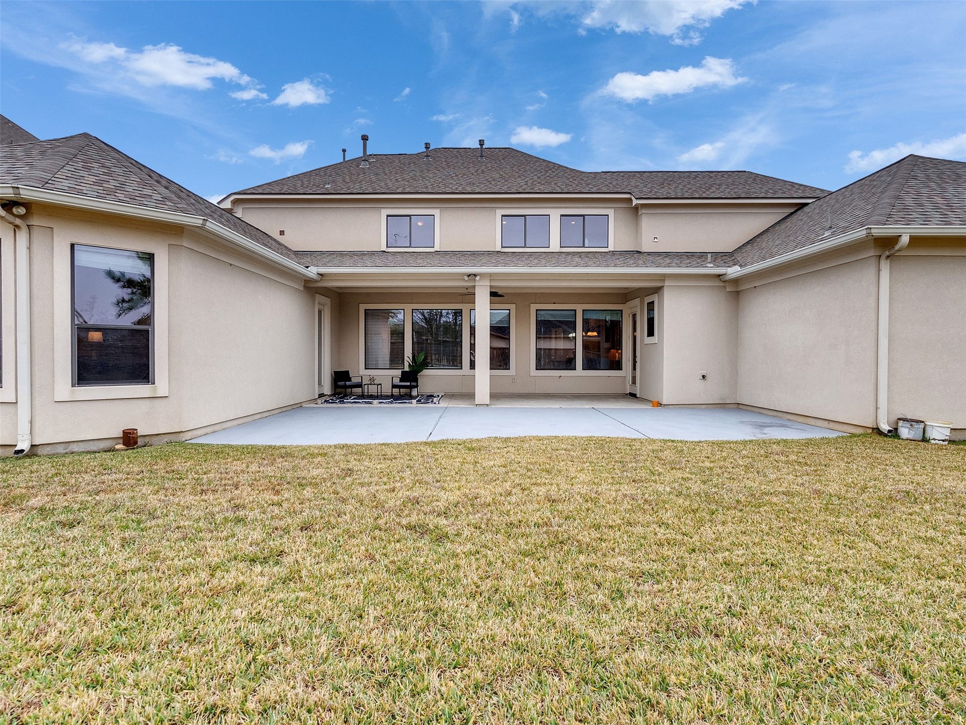 6914 Sandwedge Point Court, Spring, TX 77389 Spacious backyard with a well-maintained lawn and a large concrete patio area, perfect for outdoor seating. The house features a two-story exterior with multiple windows, offering ample natural light inside. The covered patio area provides a cozy space for relaxation or entertaining.