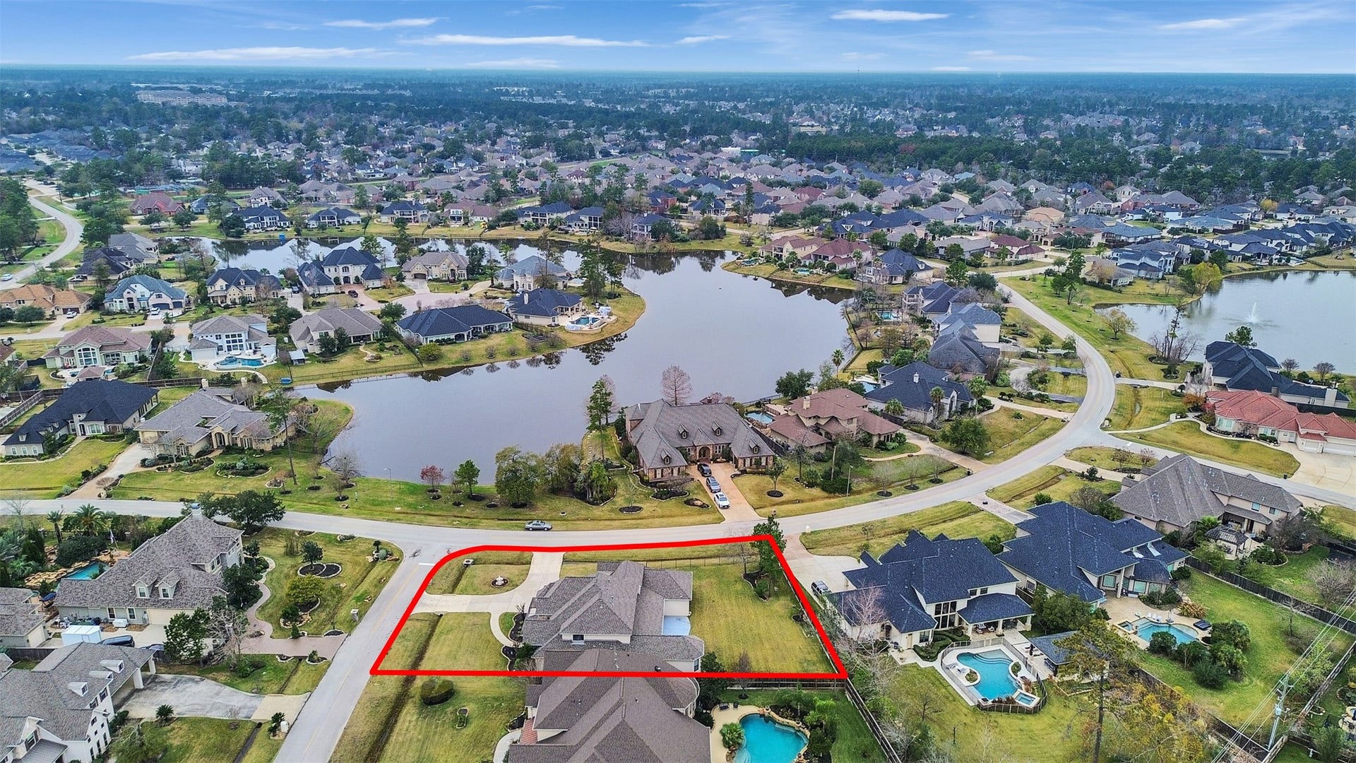 6914 Sandwedge Point Court, Spring, TX 77389 This photo showcases a spacious home outlined in red, situated in a picturesque neighborhood with lush greenery and scenic water views. The property is in a well-planned community featuring large homes, landscaped yards, and nearby lakes, offering a serene and upscale living environment.