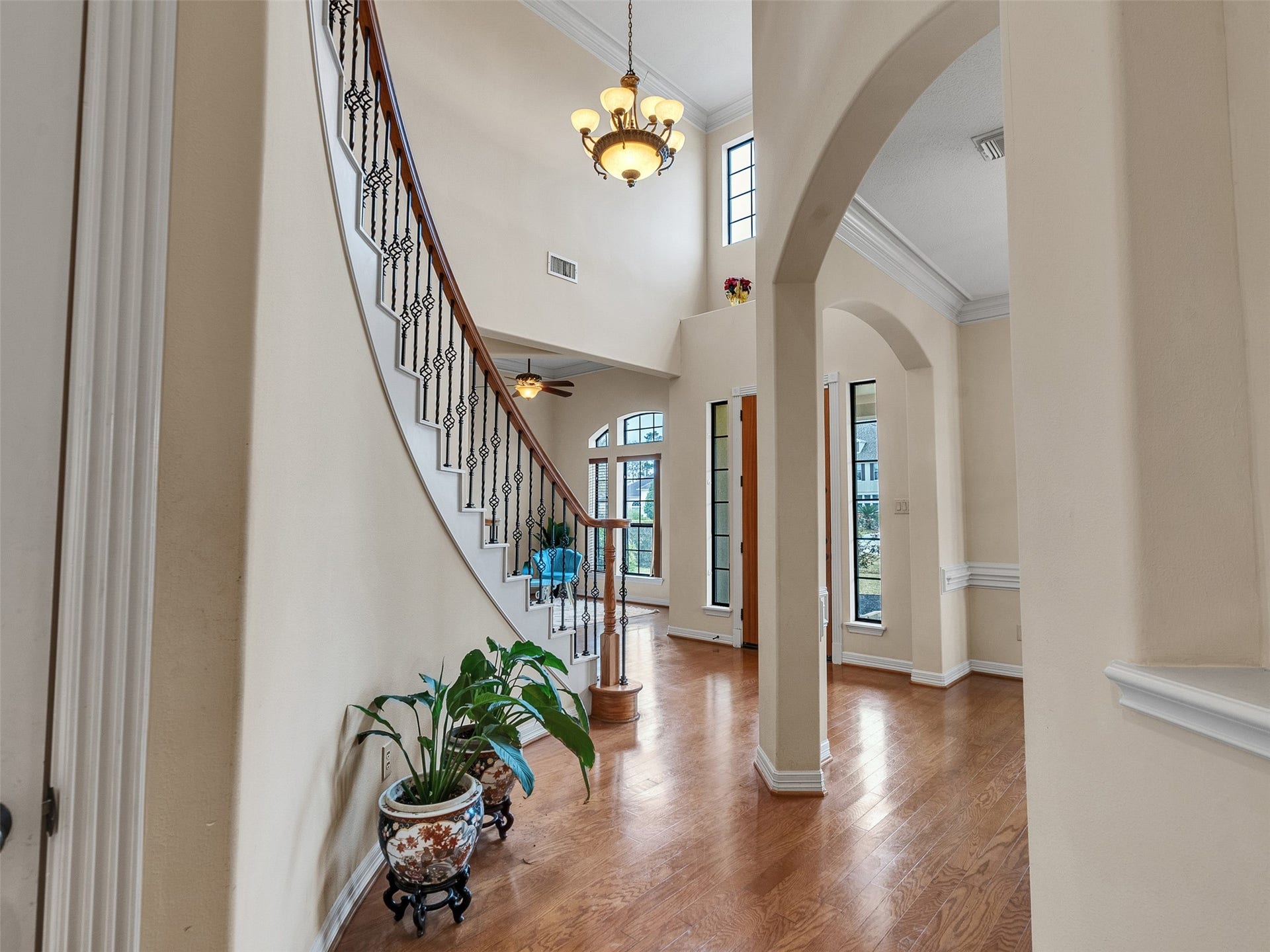 6914 Sandwedge Point Court, Spring, TX 77389 This elegant entryway features a grand curved staircase with wrought iron railings, hardwood floors, and high ceilings. Large windows provide ample natural light, while arched doorways add a touch of sophistication.