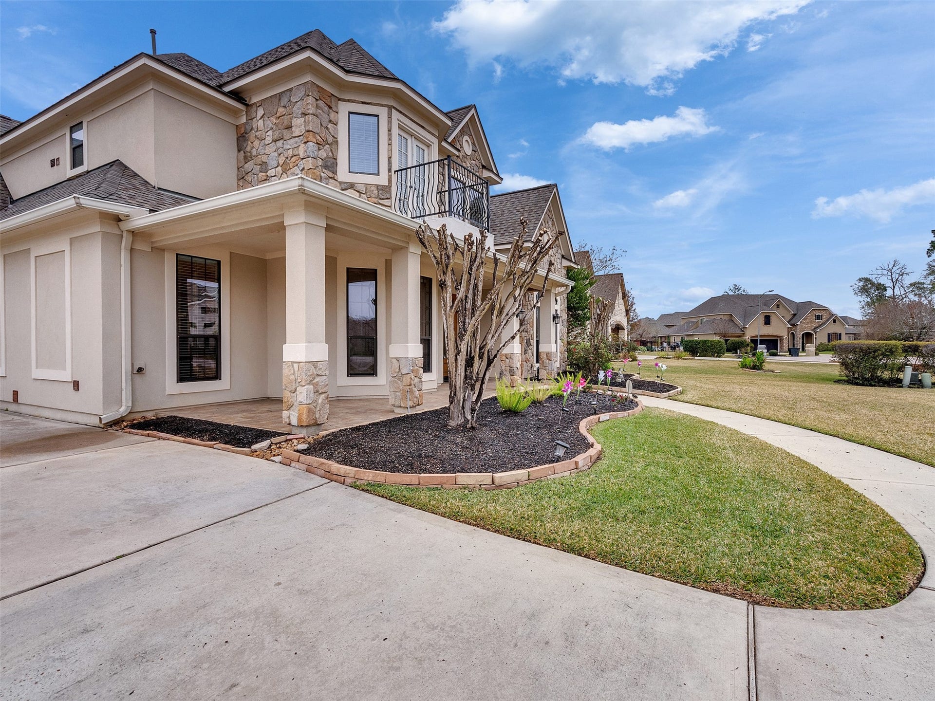 6914 Sandwedge Point Court, Spring, TX 77389 Modern two-story home with stone and stucco exterior, a covered porch, and well-maintained landscaping. The property features a spacious driveway and a manicured lawn, set in a quiet neighborhood with similar styled homes.