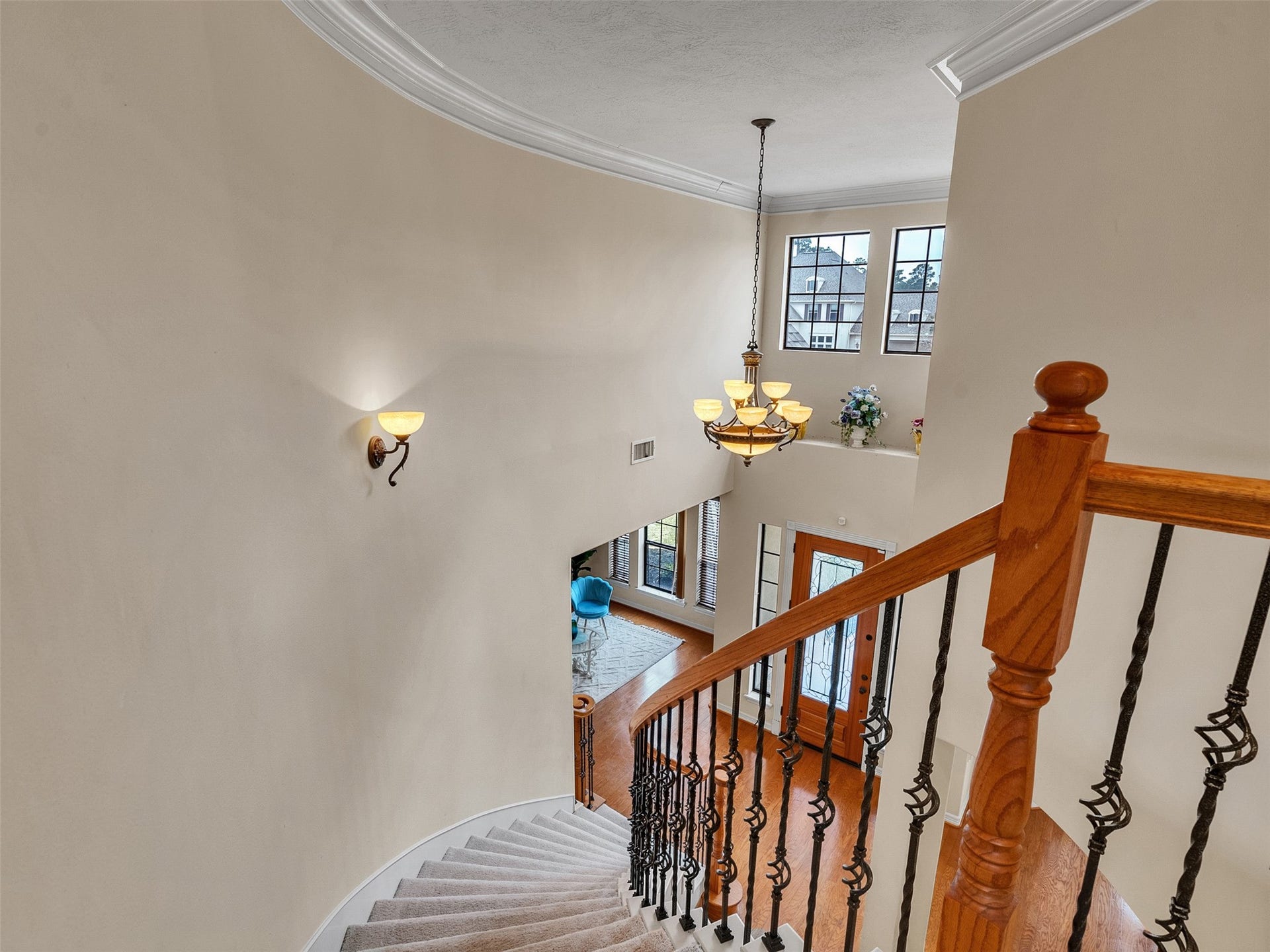 6914 Sandwedge Point Court, Spring, TX 77389 This elegant foyer features a curved staircase with wooden handrails and iron spindles, leading to a bright, two-story entryway. A stylish chandelier and large windows provide ample natural light, highlighting the open layout and warm hardwood floors below.