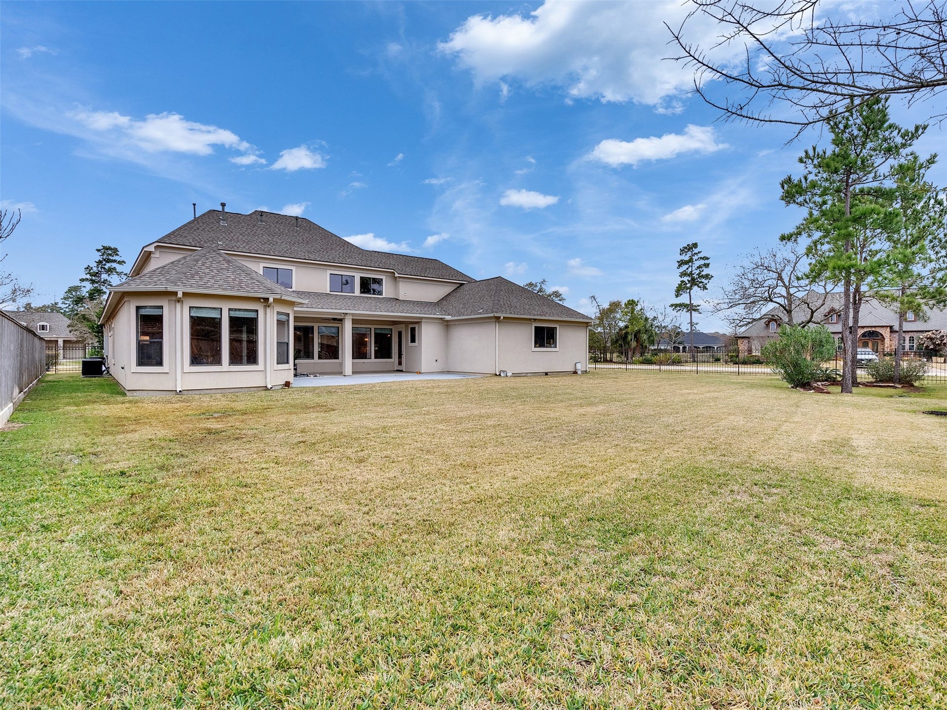 6914 Sandwedge Point Court, Spring, TX 77389 Spacious backyard with a large, two-story home featuring numerous windows. The area is well-maintained, offering ample outdoor space, and is surrounded by mature trees. Ideal for family activities and entertaining.