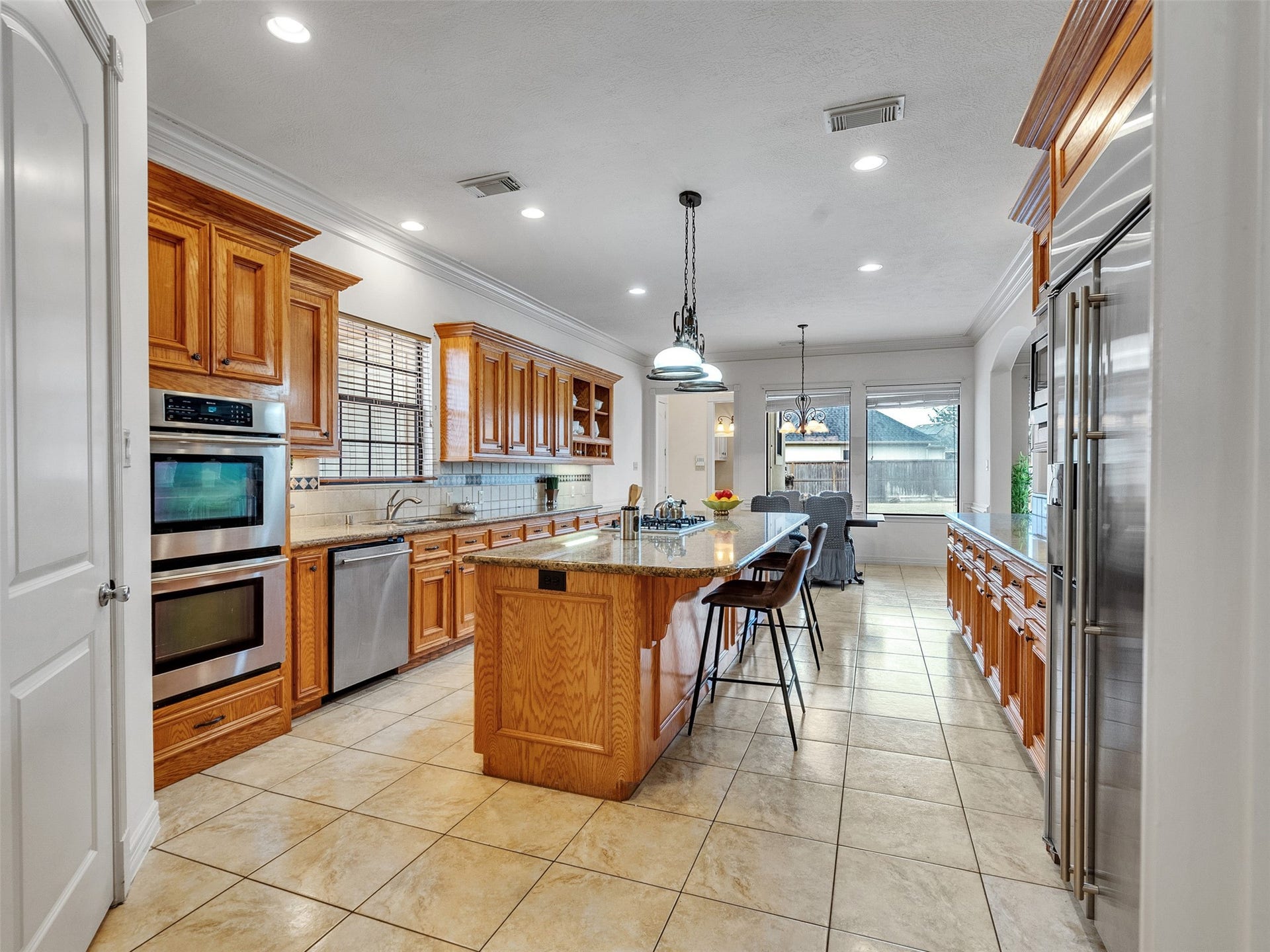 6914 Sandwedge Point Court, Spring, TX 77389 Bright and spacious kitchen with ample natural light, featuring wooden cabinetry, granite countertops, stainless steel appliances, and a central island with seating. Ideal for cooking and entertaining.
