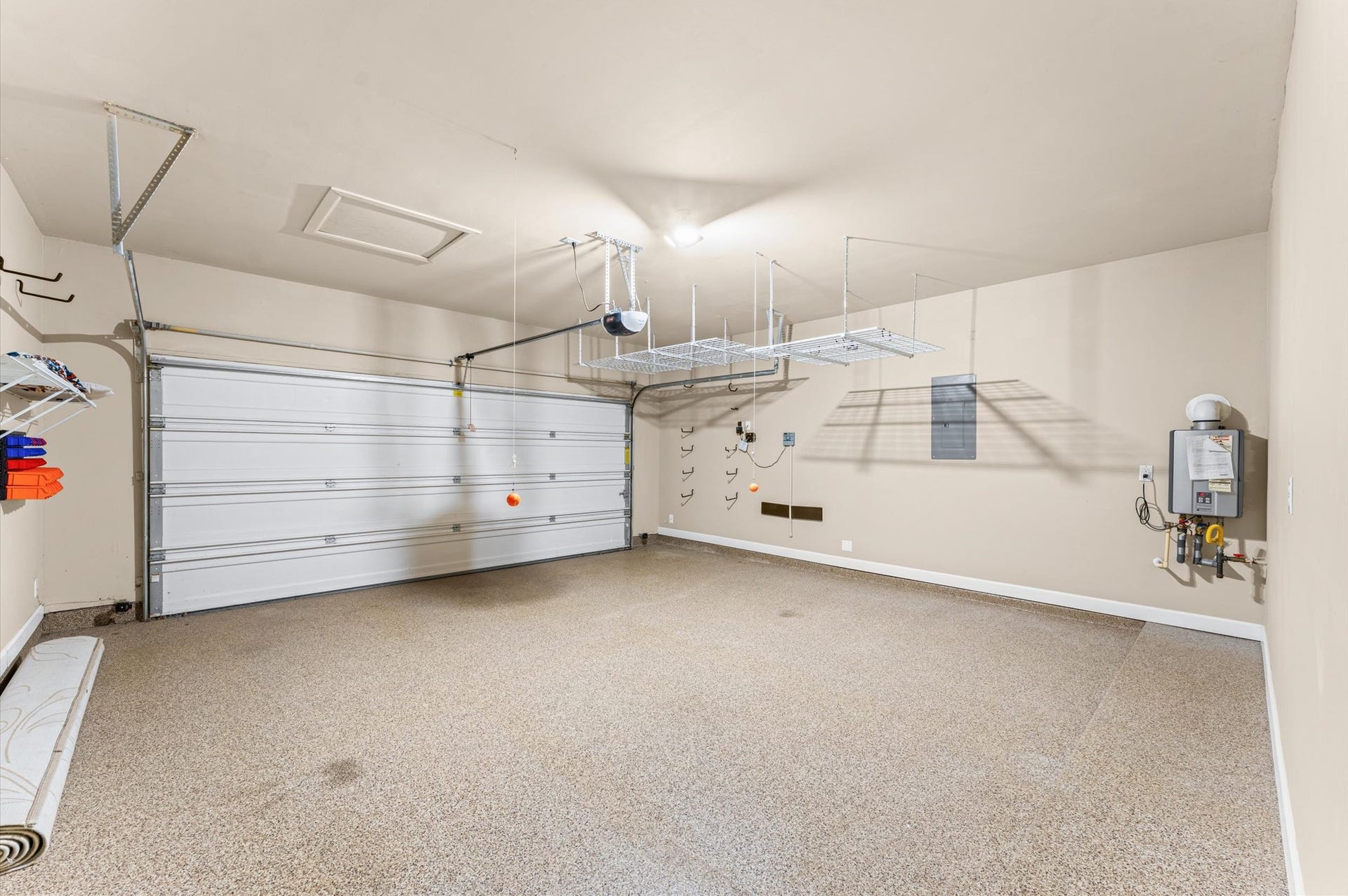 2-car garage with epoxy floors, overhead ceiling storage, and a tankless water heater.