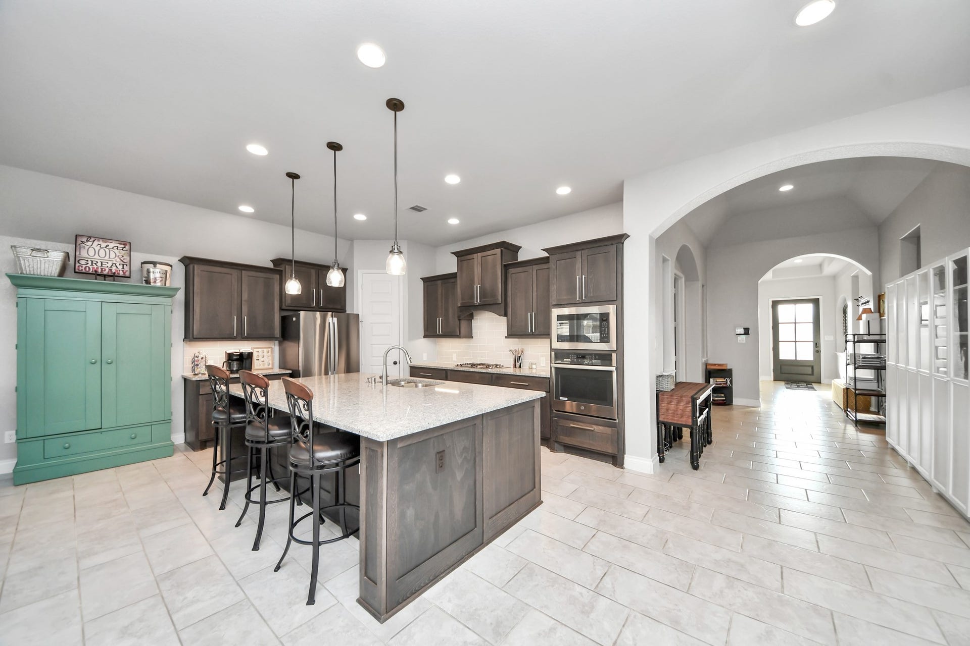 3211 Sweet Audrey Lane, Richmond, TX 77406 Spacious kitchen with an oversized island, stainless steel appliances, and arched openings to the wide gallery hall.