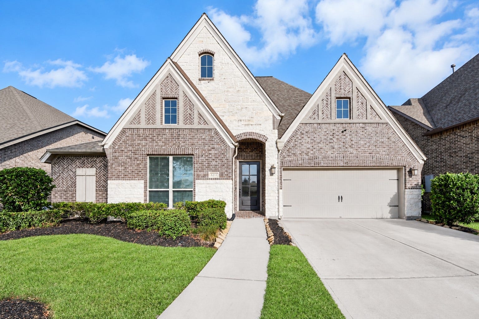 3211 Sweet Audrey Lane, Richmond, TX 77406 Classic curb appeal with complimentary brick and stone, decorative gable detail, glass-panel front door, and a two-car attached garage.