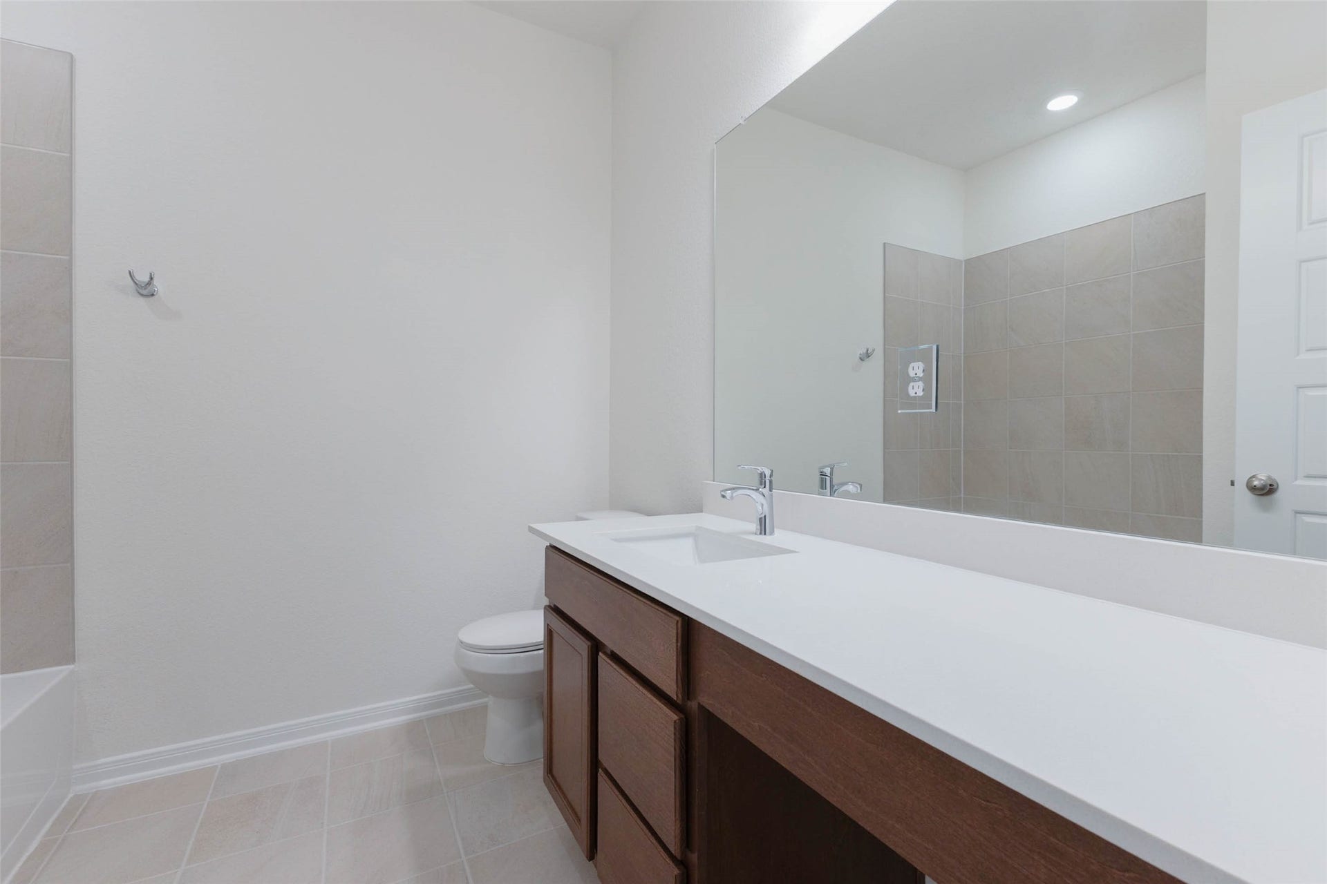 The secondary full bath features an extended vanity with knee space and a wide mirror.