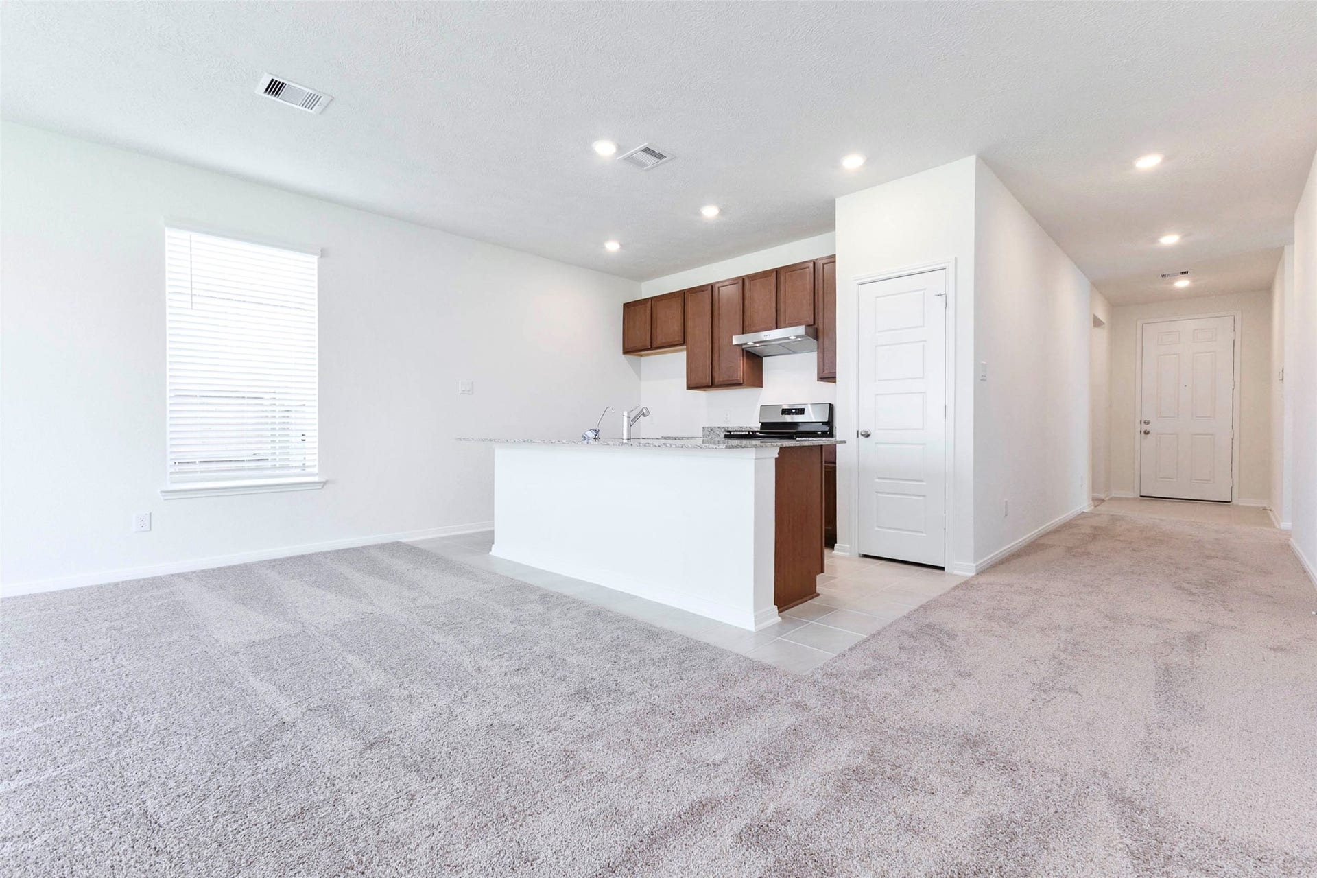 The kitchen anchors the main living area, with a granite island, Woodmont cabinetry and a pantry.