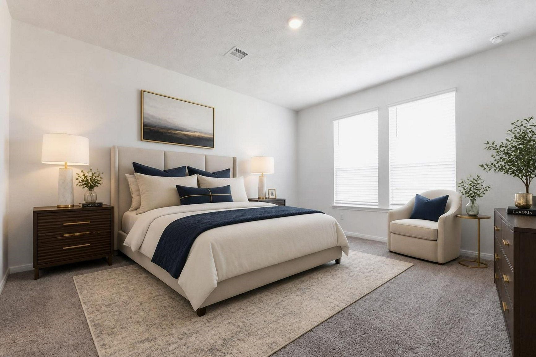 Virtually staged. The primary suite is shown with a king bed, nightstands and a sitting chair.