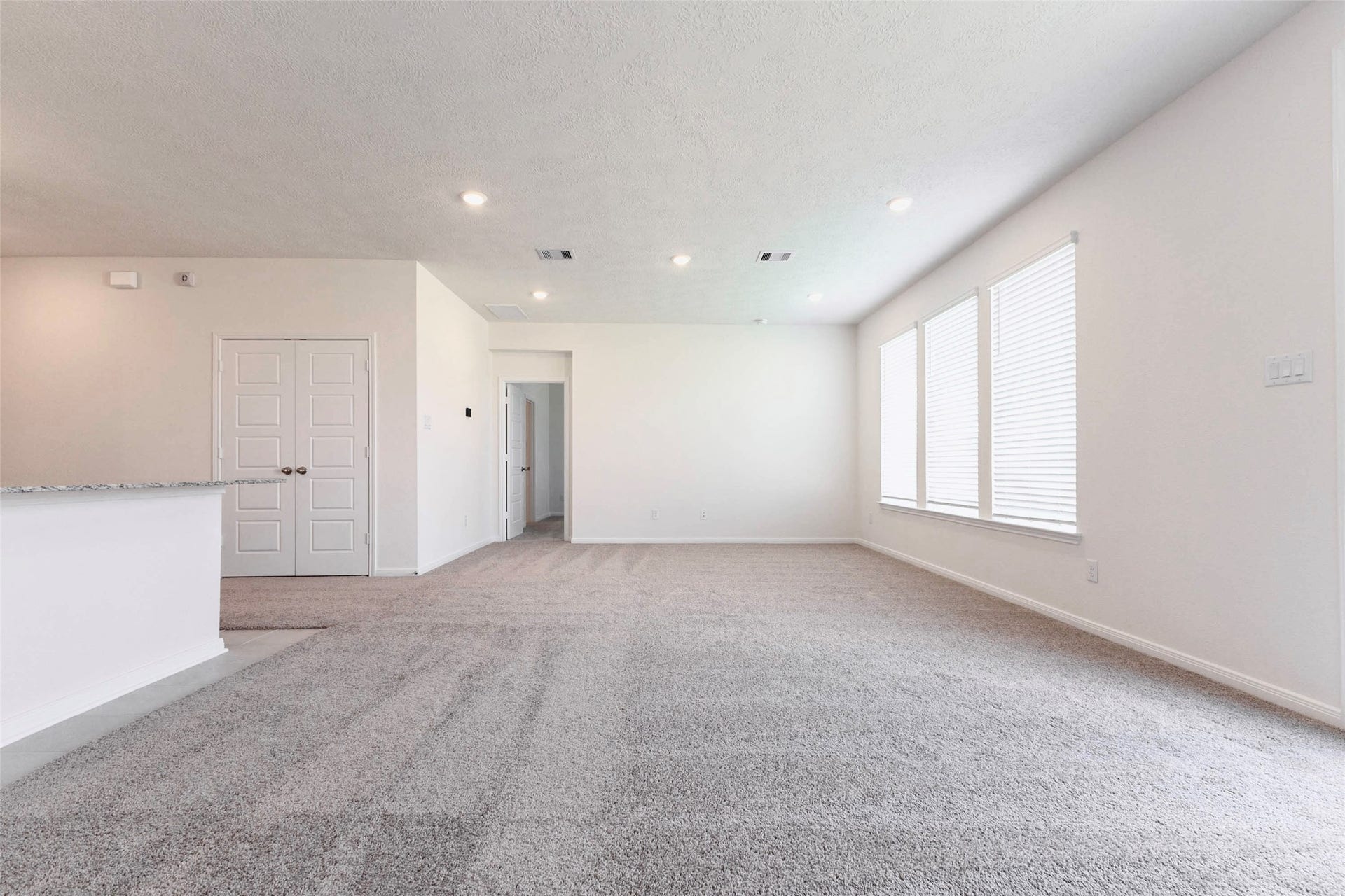 A wall of three windows fills the family room with natural light, with recessed lighting throughout.