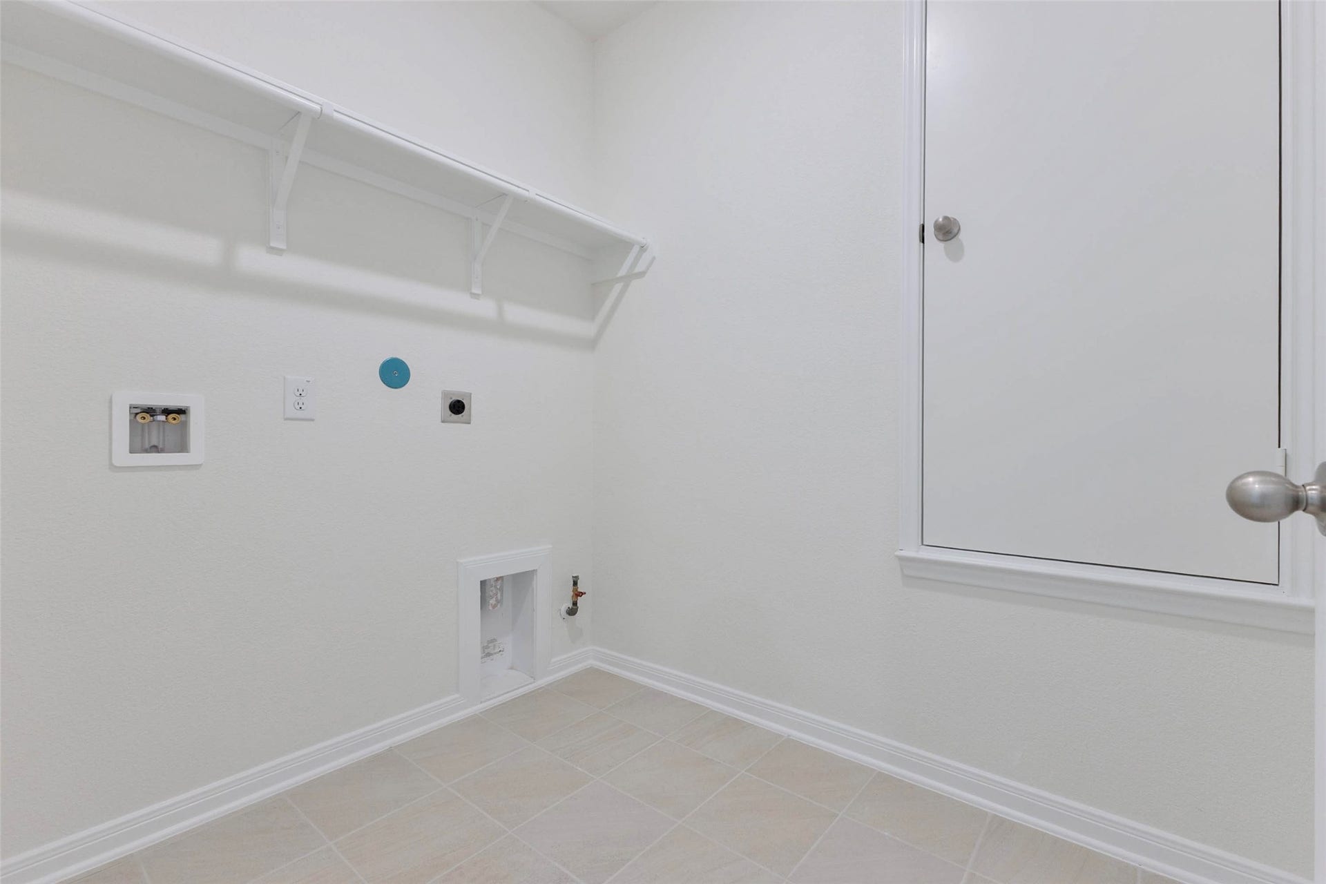 The dedicated utility room offers a storage shelf and both gas and electric dryer connections.
