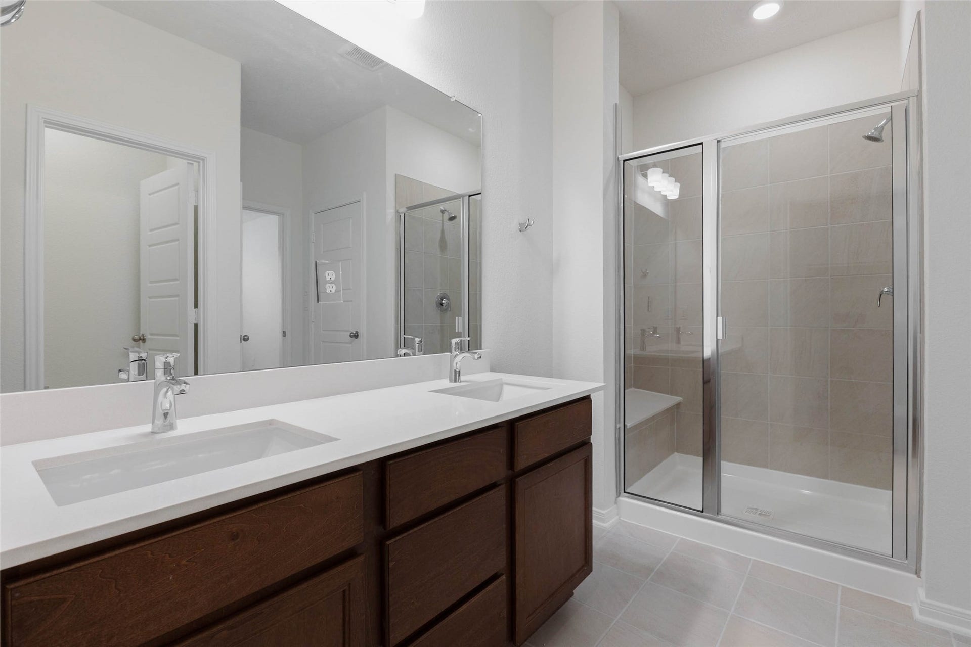 The primary bath features a dual sink vanity and a glass-enclosed walk in shower with seat.