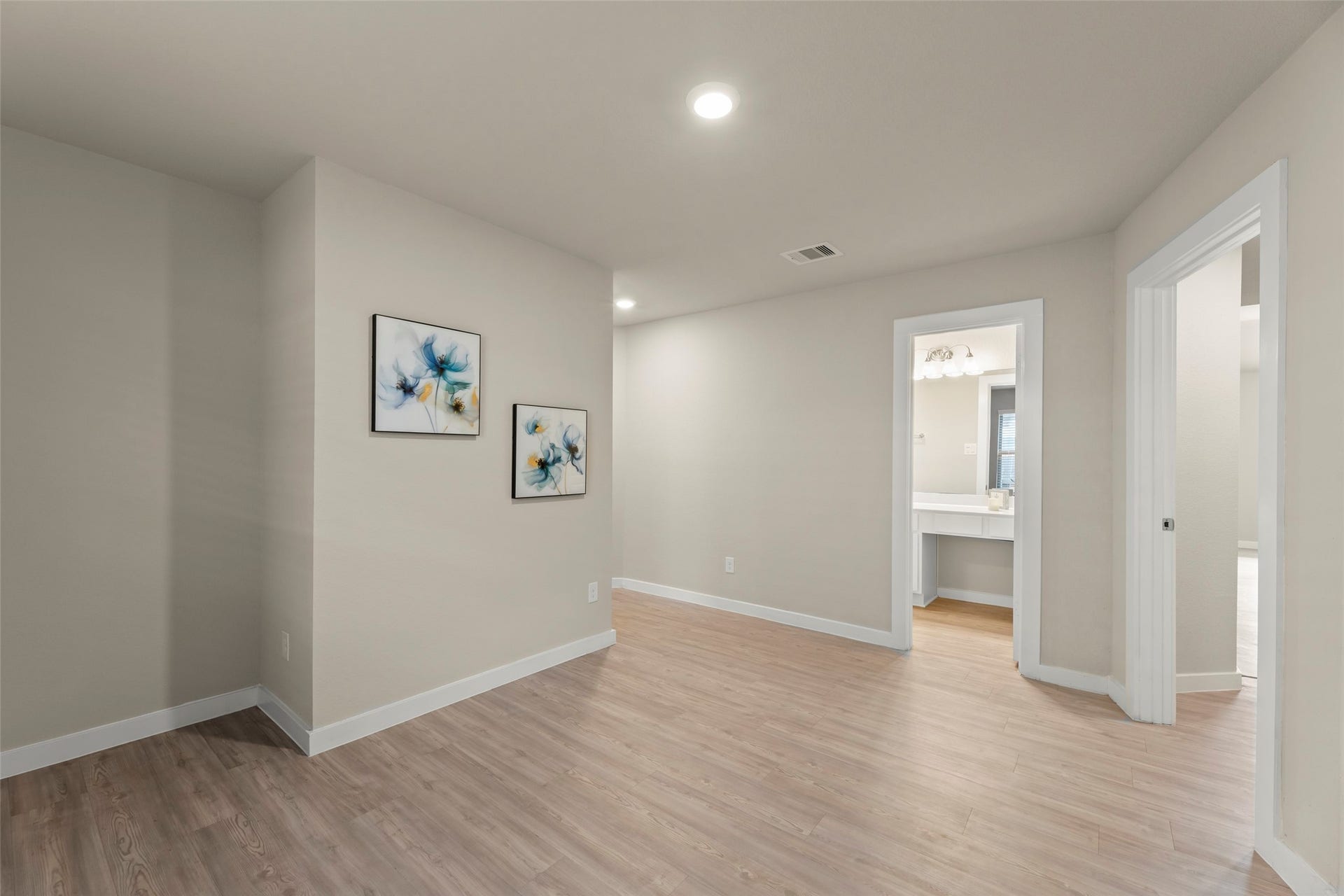 2610 Blue Abbot Drive, Fresno, TX 77545 Elegant wood flooring, neutral walls with modern floral artwork, and access to a bright bathroom.