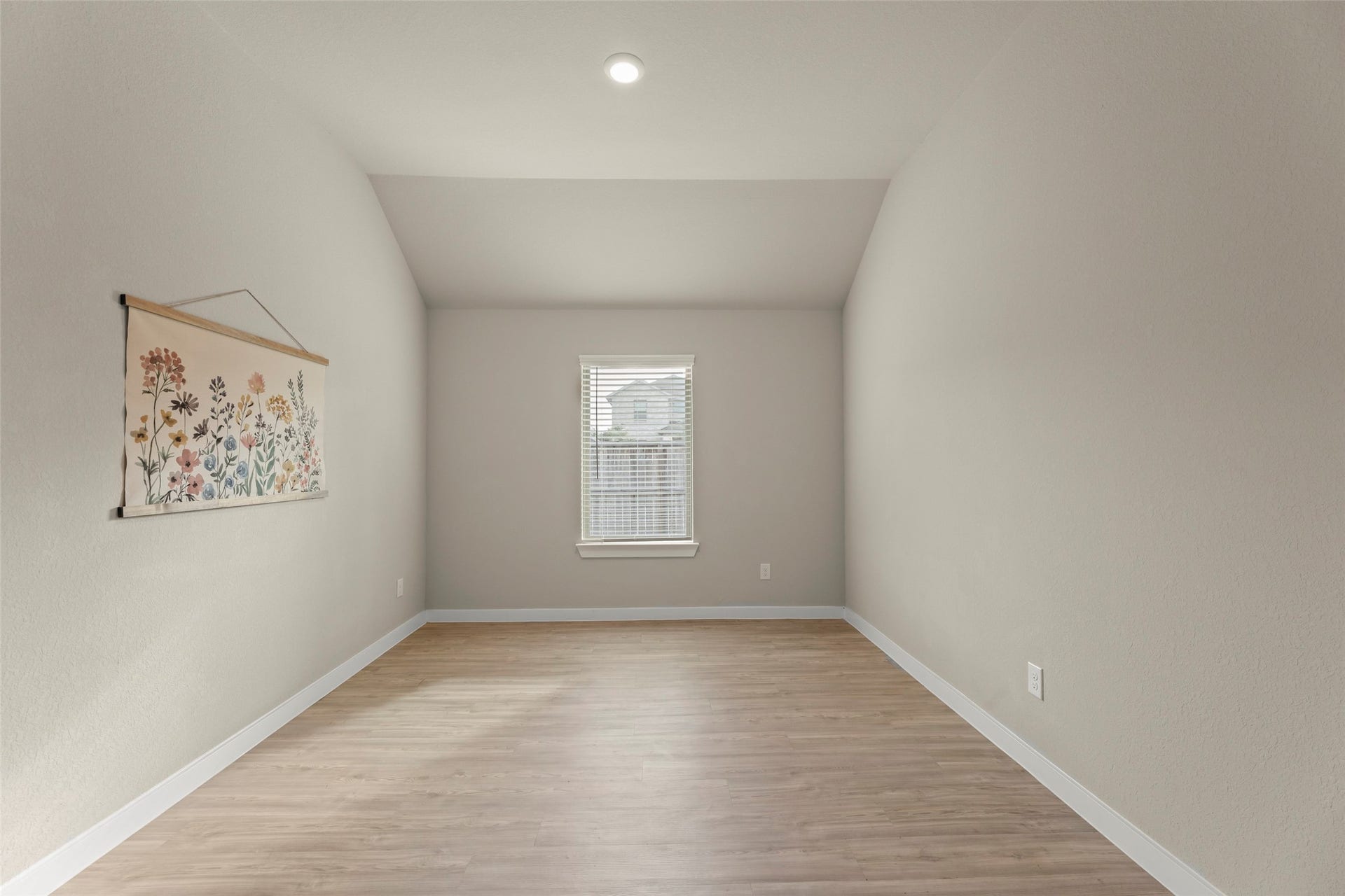 2610 Blue Abbot Drive, Fresno, TX 77545 Bright and spacious room with sleek hardwood floors and neutral walls, featuring a window that allows natural light to fill the space, complemented by a charming floral wall hanging.