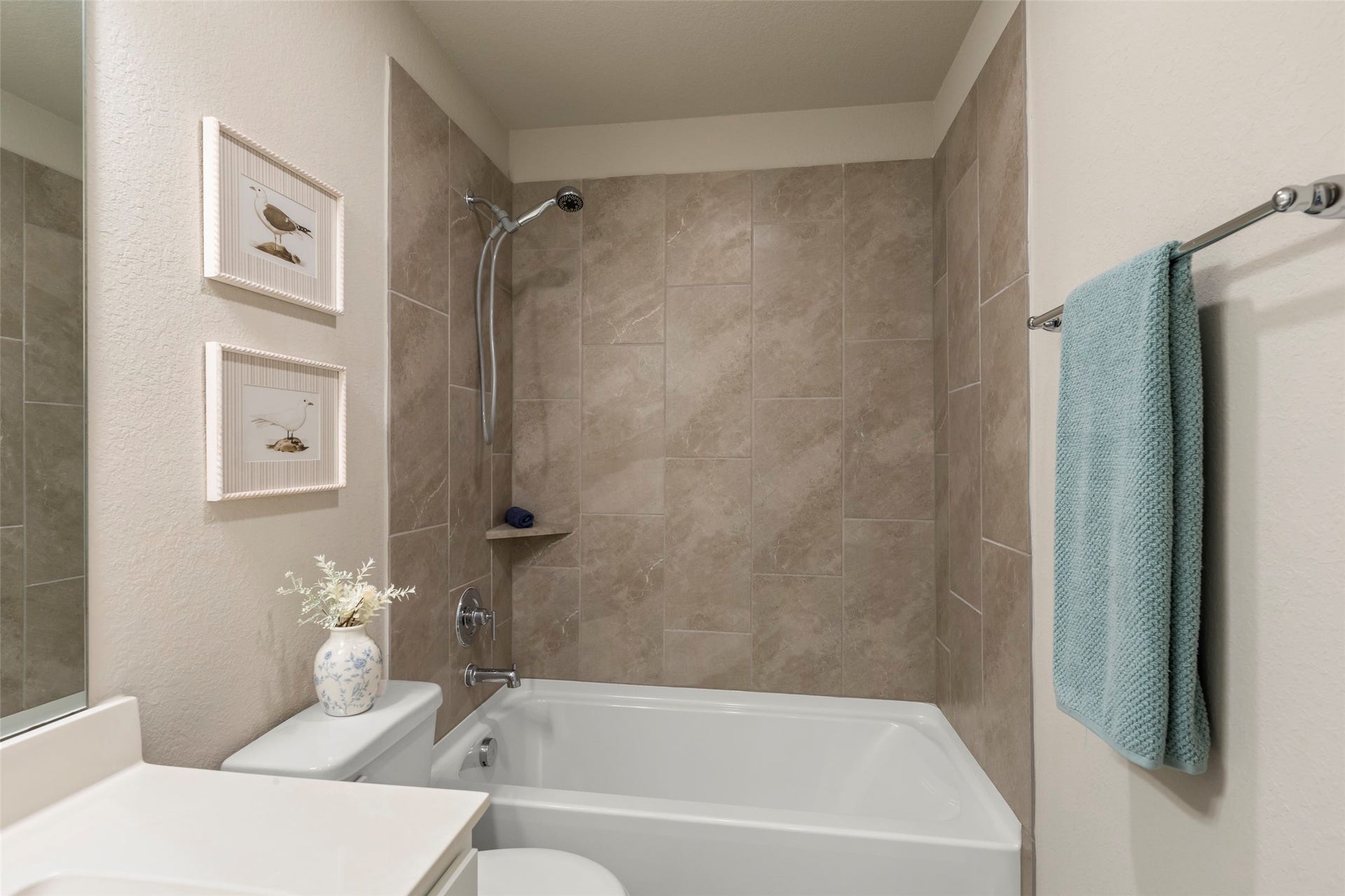 2610 Blue Abbot Drive, Fresno, TX 77545 Modern bathroom featuring elegant beige tilework, a sleek bathtub with a shower, and tasteful decor accents for a serene atmosphere.