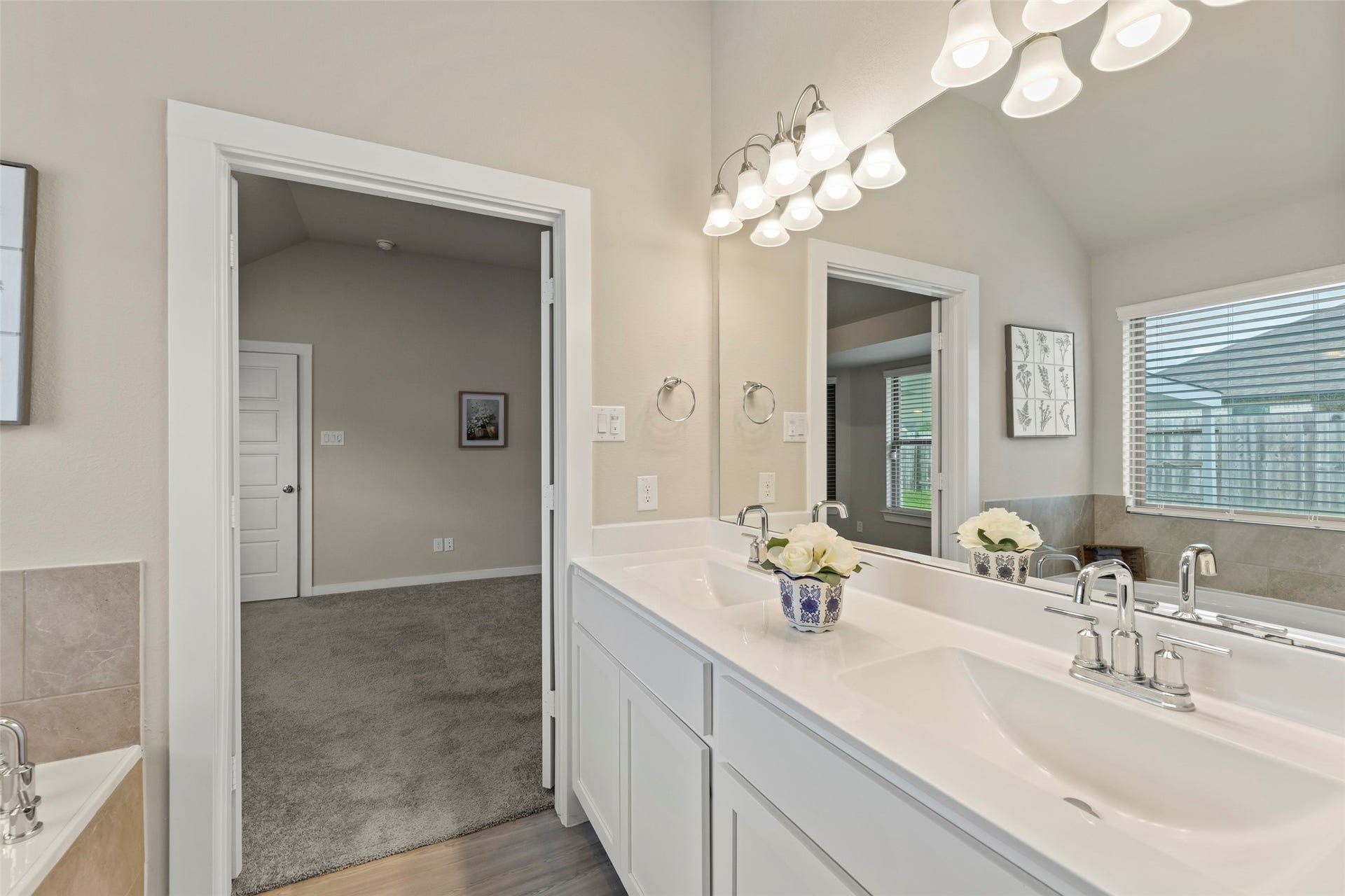 2610 Blue Abbot Drive, Fresno, TX 77545 Primary bathroom featuring a double vanity with elegant fixtures, ample lighting, and a large mirror, adjacent to a cozy carpeted bedroom.