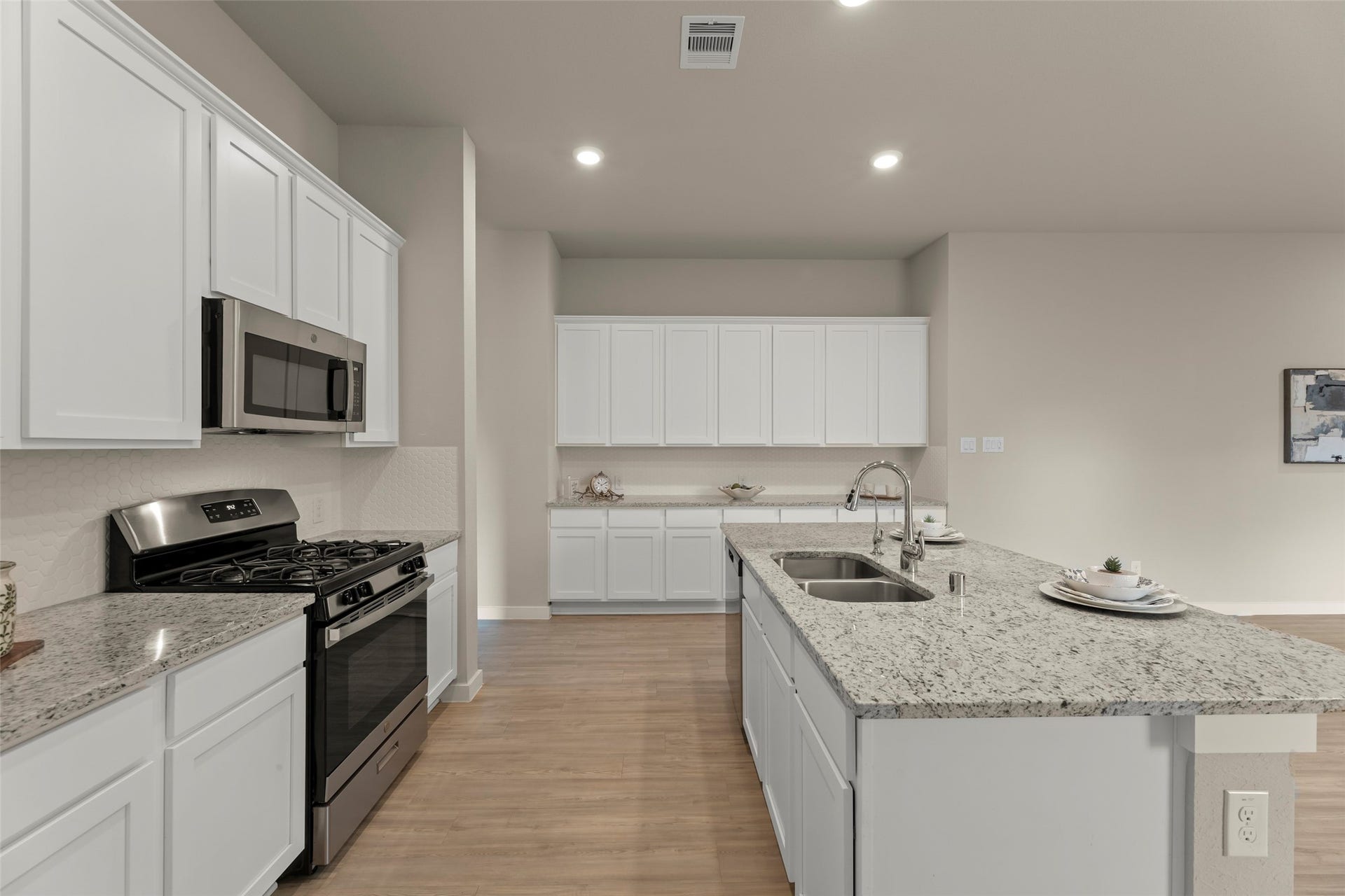 2610 Blue Abbot Drive, Fresno, TX 77545 Modern kitchen featuring sleek granite countertops, a spacious island with dual sinks, and stainless steel appliances, complemented by ample white cabinetry for storage.