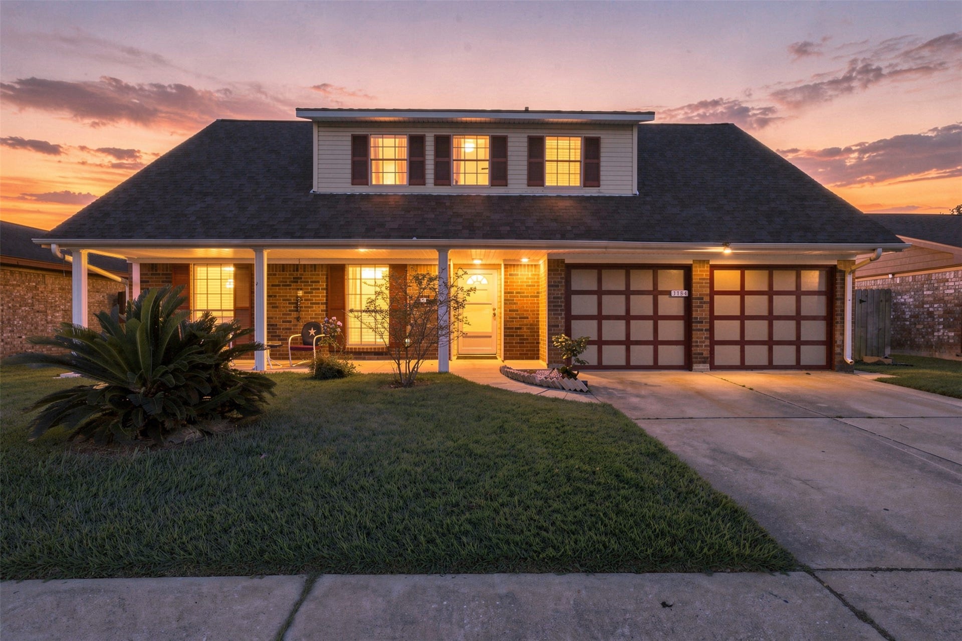 Welcoming twilight view highlighting the homes traditional exterior and attached two-car garage.