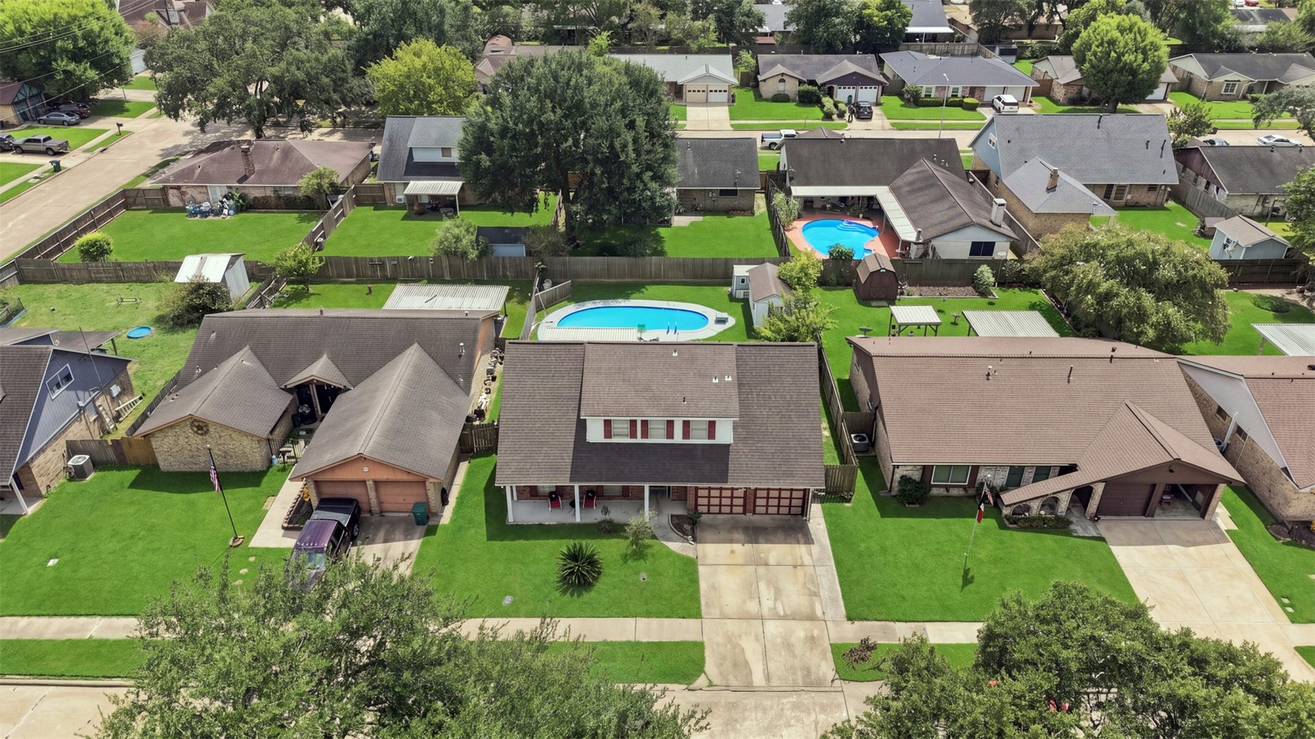 Aerial view showcasing the home, backyard pool, and surrounding neighborhood.