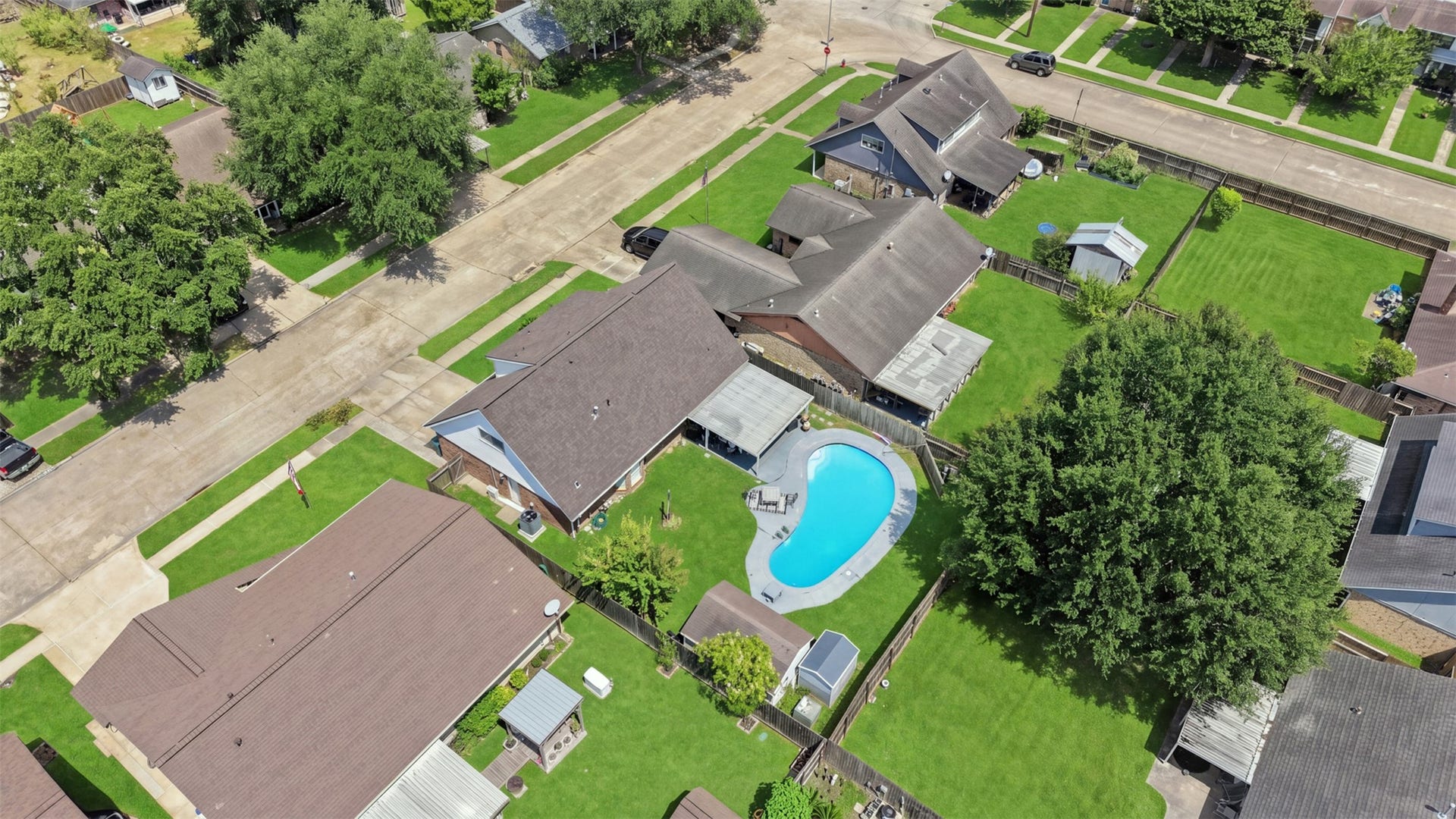 Elevated view showcases the propertys backyard, pool, and surrounding residential setting.