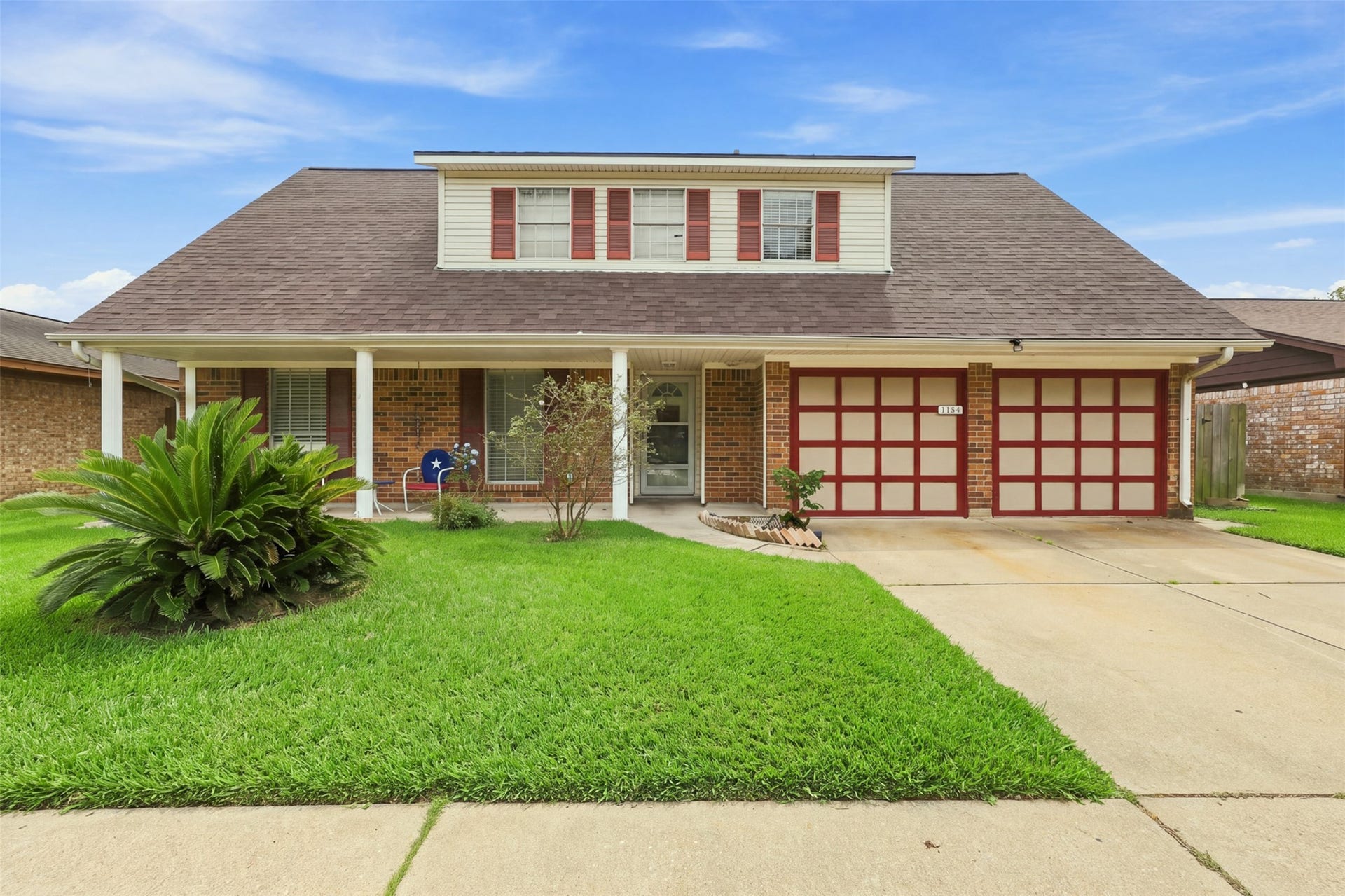 Classic front exterior featuring brick construction, an attached two-car garage, and covered entry.