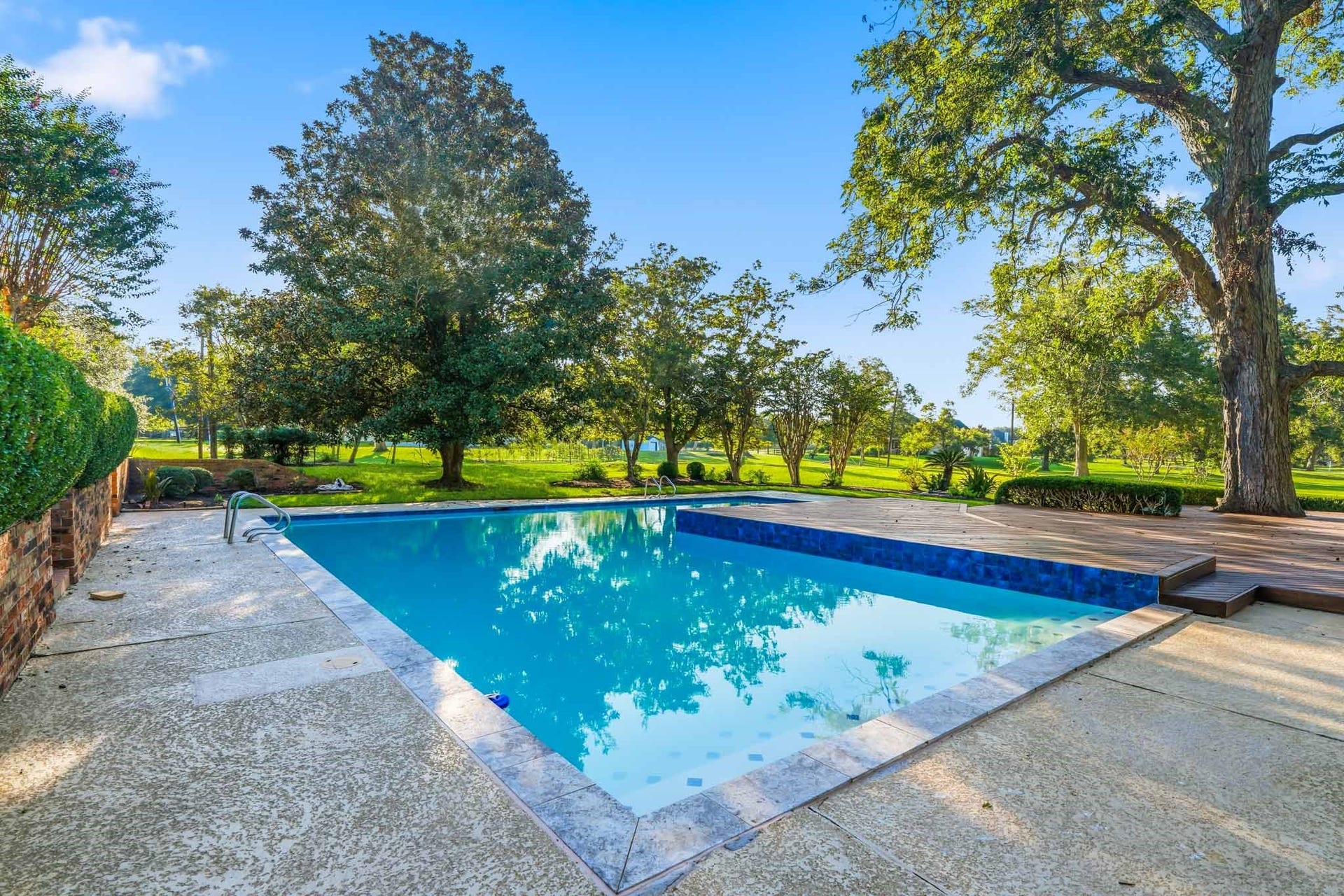 218 Bella Vista Drive, Richmond, TX 77406 Serene backyard oasis featuring a sparkling pool surrounded by lush greenery and mature trees, perfect for relaxation and entertaining.