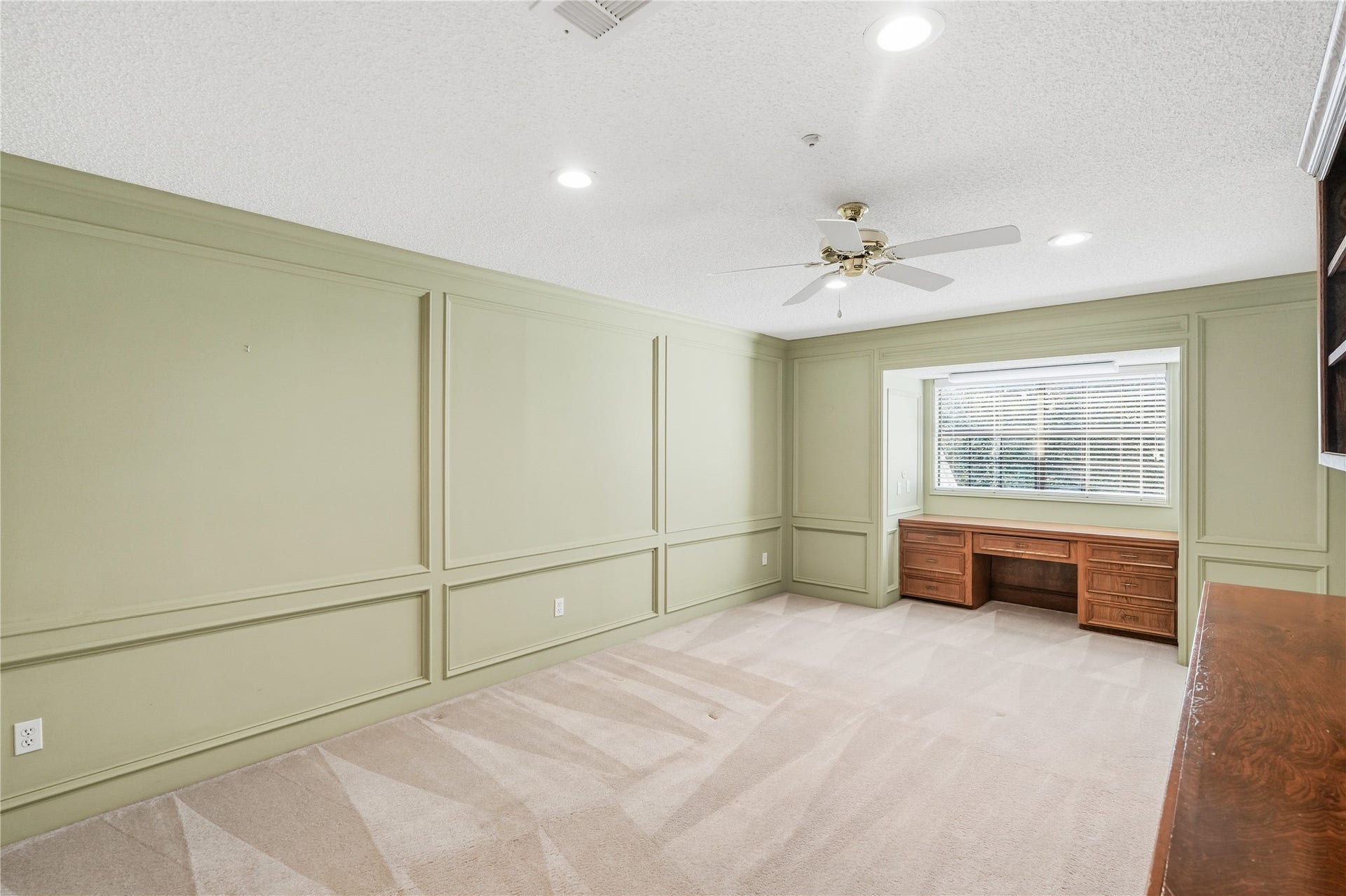 218 Bella Vista Drive, Richmond, TX 77406 Spacious room with green wainscoting, plush carpet, a large window for natural light, and a built-in wooden desk, perfect for family or guests.