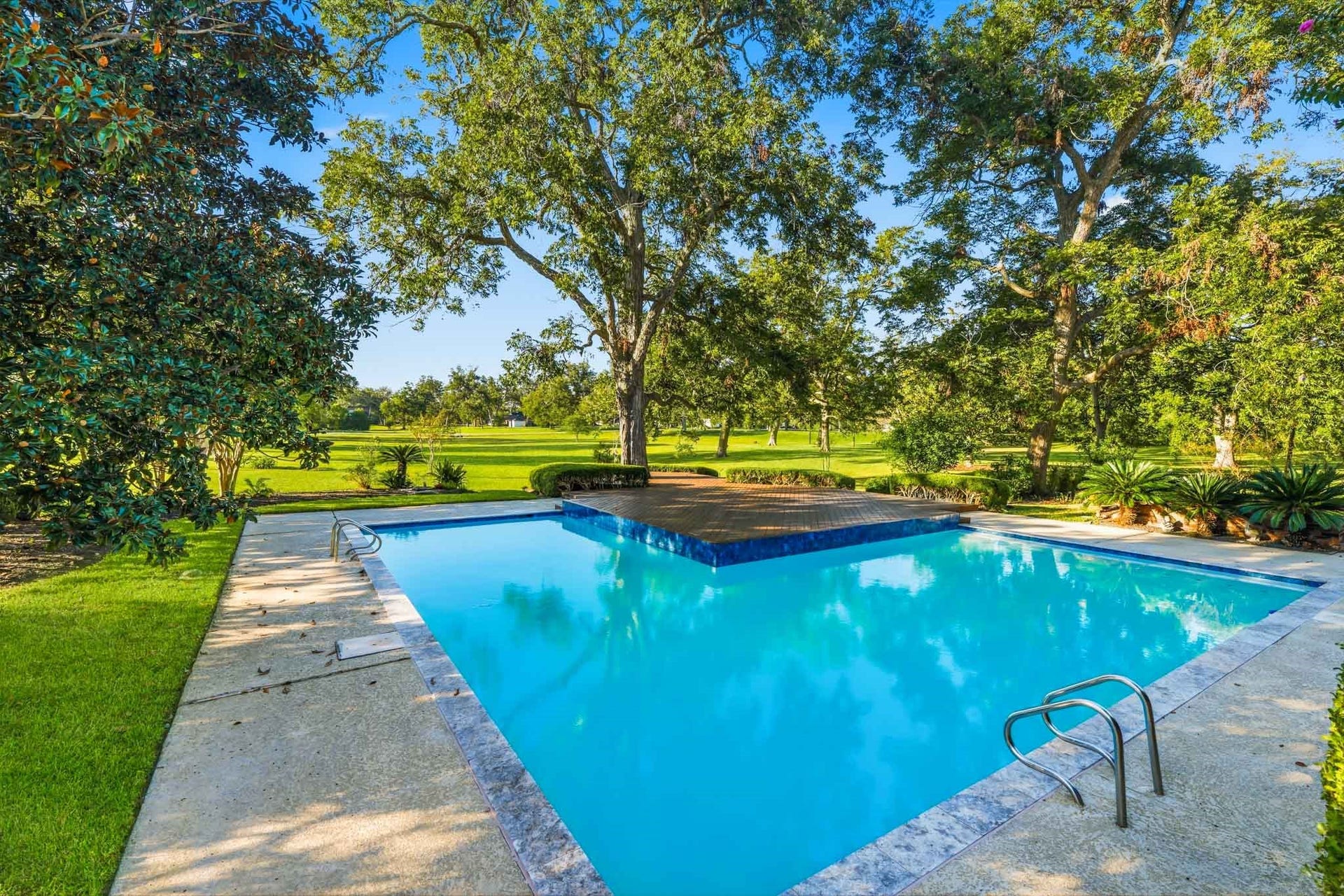 218 Bella Vista Drive, Richmond, TX 77406 Enjoy outdoor living with a sparkling pool surrounded by greenery and trees, offering a perfect retreat.