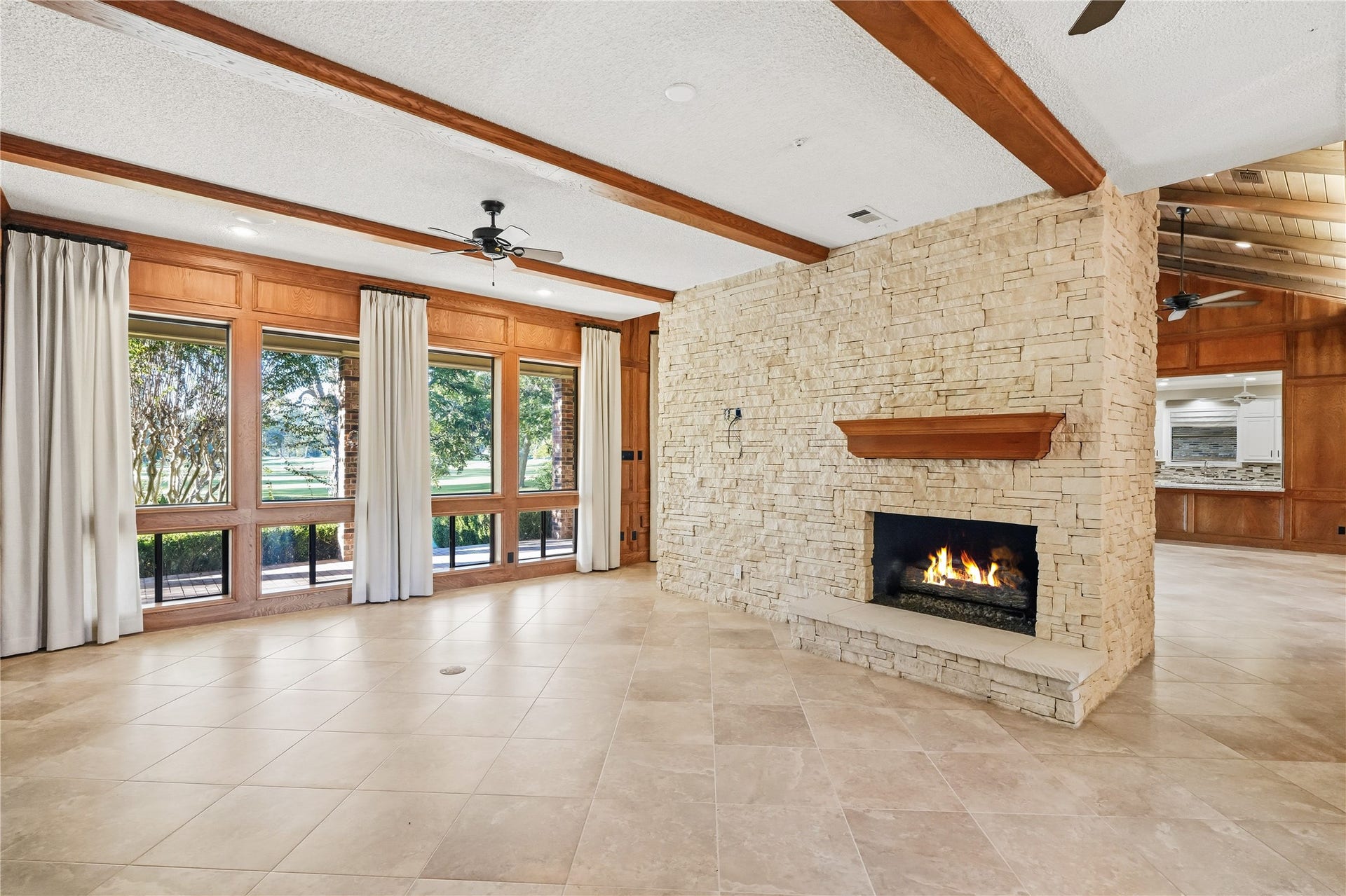218 Bella Vista Drive, Richmond, TX 77406 Spacious living area featuring a stunning stone fireplace, large windows with serene views, and elegant tile flooring.