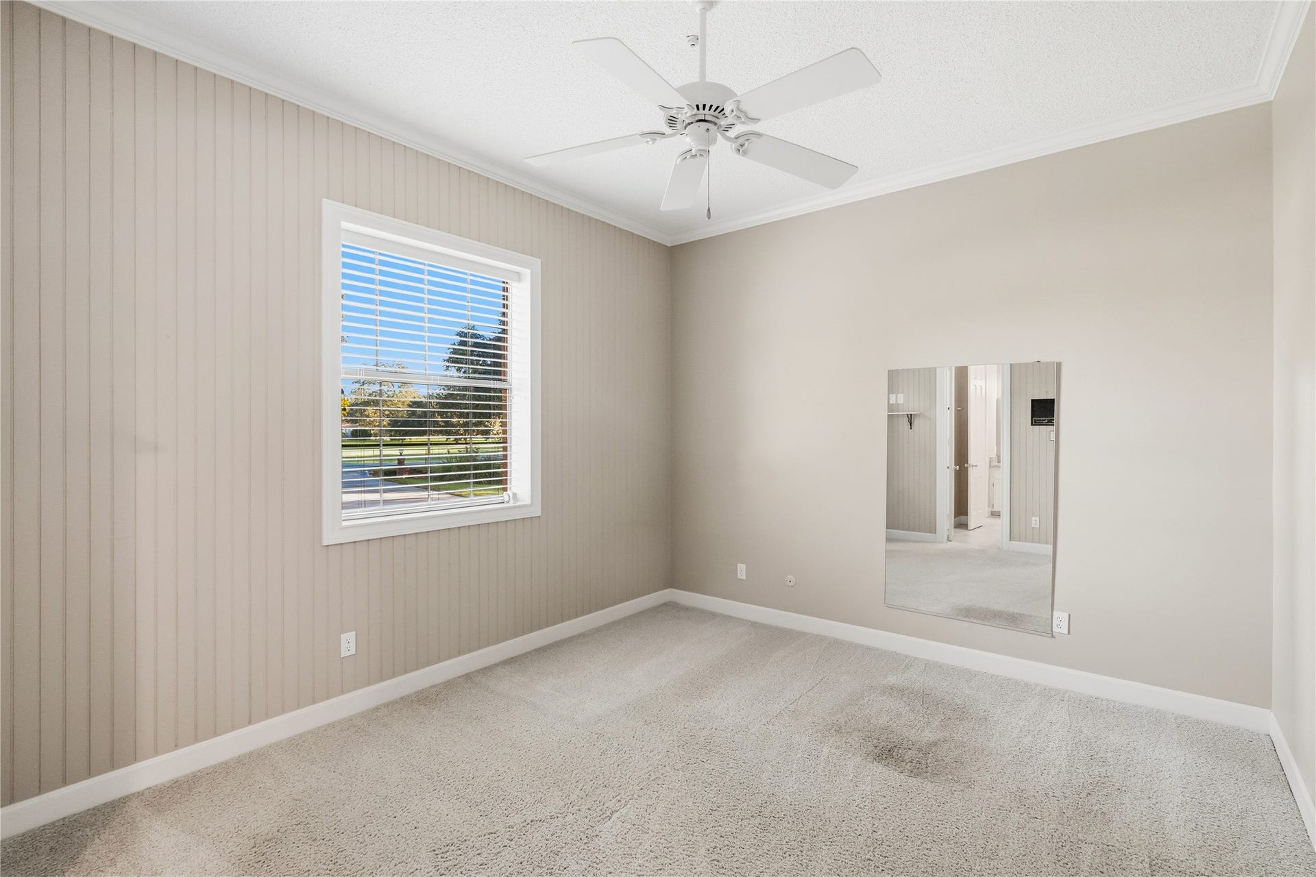 218 Bella Vista Drive, Richmond, TX 77406 Bright room with neutral tones, featuring a large window with blinds, a ceiling fan connected to a bathroom.