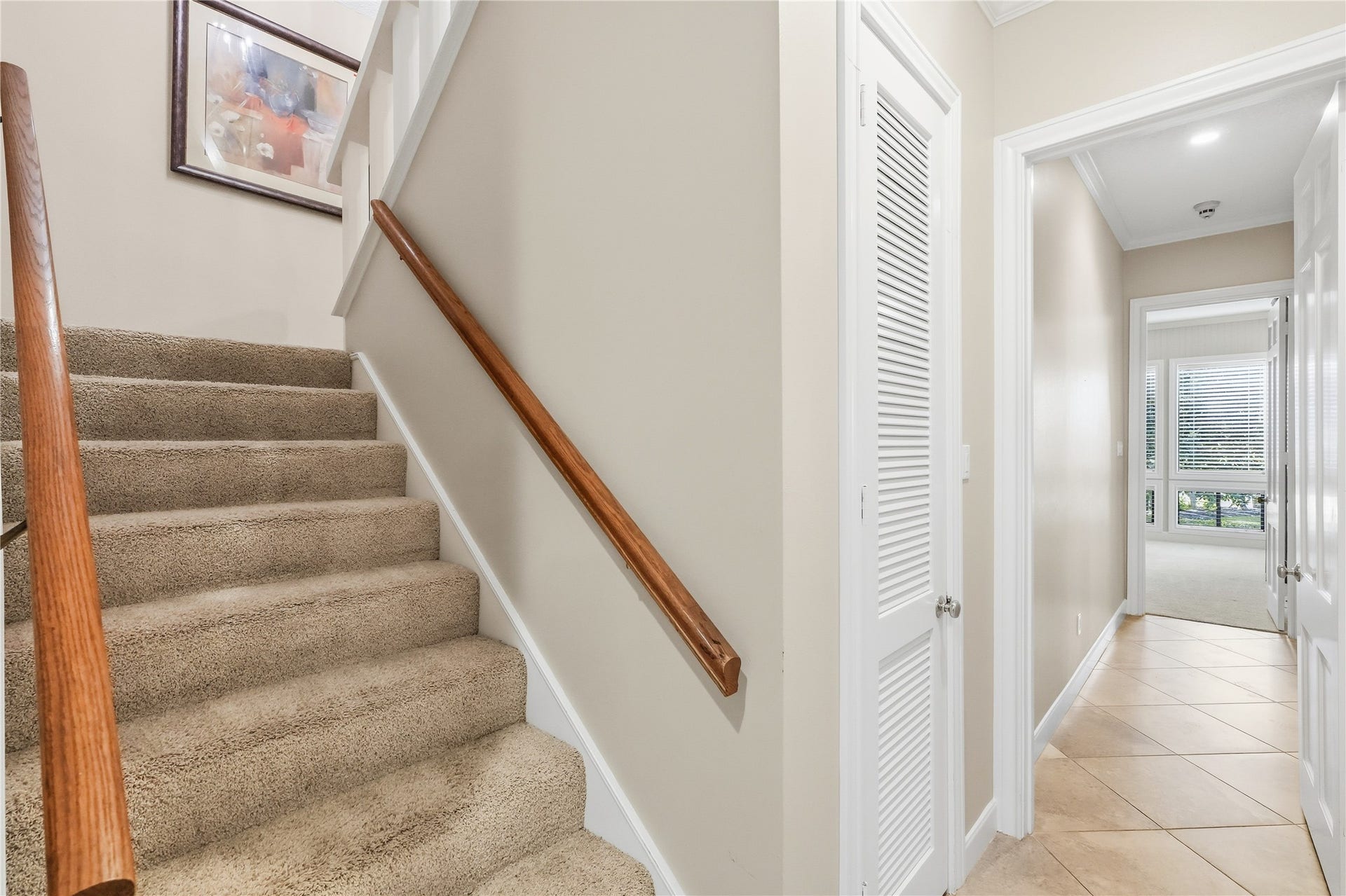 218 Bella Vista Drive, Richmond, TX 77406 Bright hallway features plush carpeted stairs with a wooden handrail leading to the upper level, while tiled flooring and ample natural light guide you towards spacious primary room with large windows.